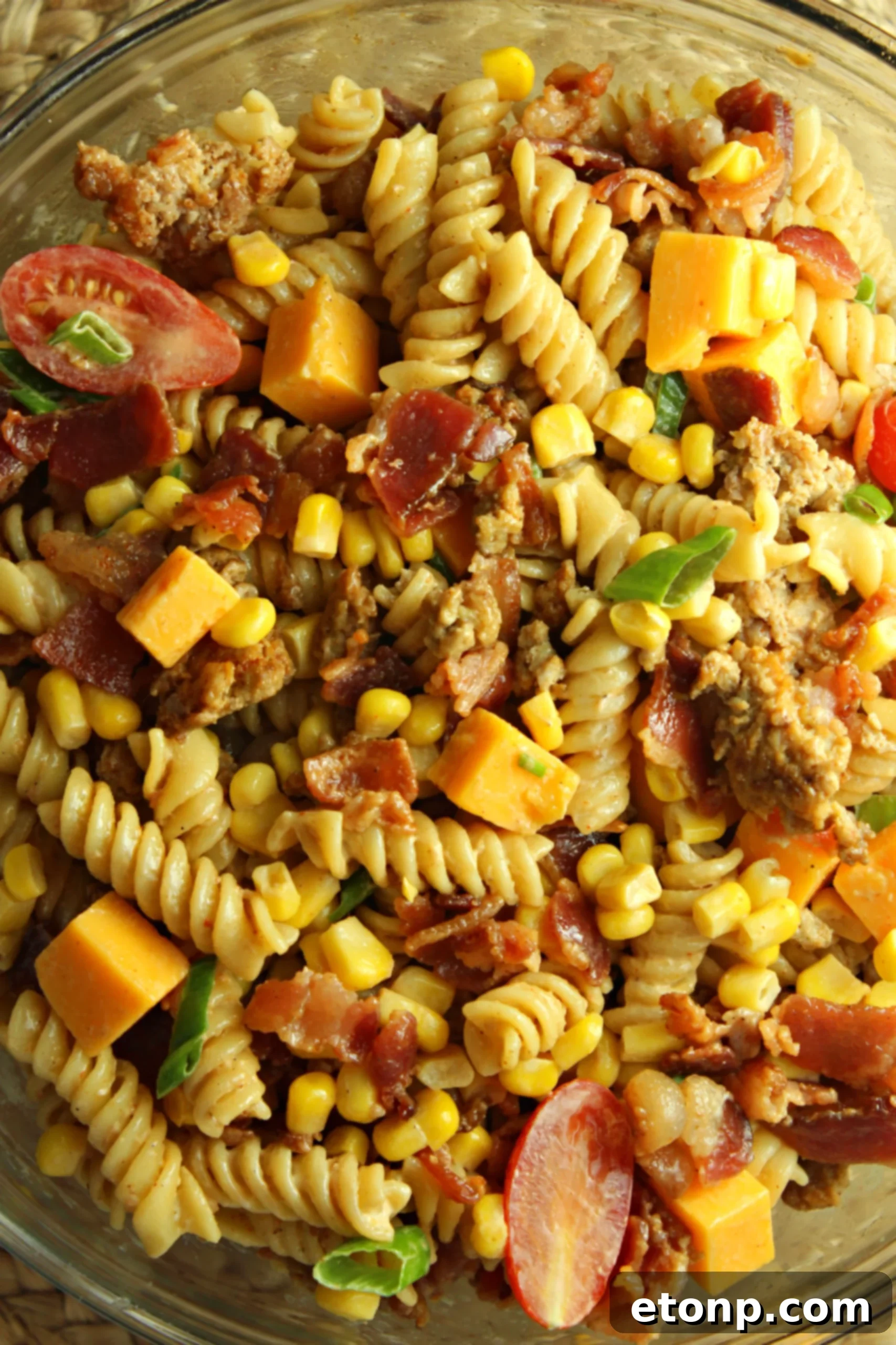 Chuckwagon Pasta Salad 4 Loaded Cowboy Pasta Salad with a fork ready to scoop, showcasing vibrant colors and textures of pasta, bacon, and vegetables.