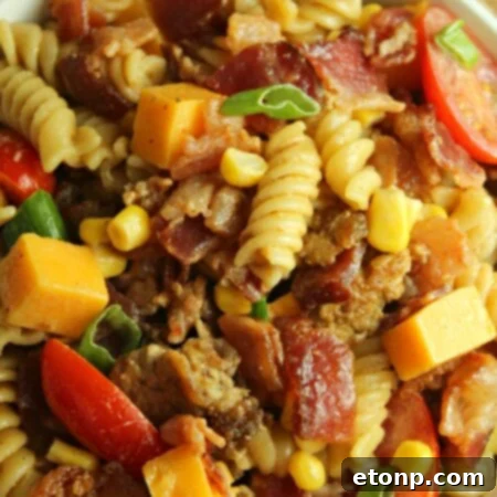 Chuckwagon Pasta Salad 10 Loaded Cowboy Pasta Salad served in a white bowl with a spoon, ready to be enjoyed.
