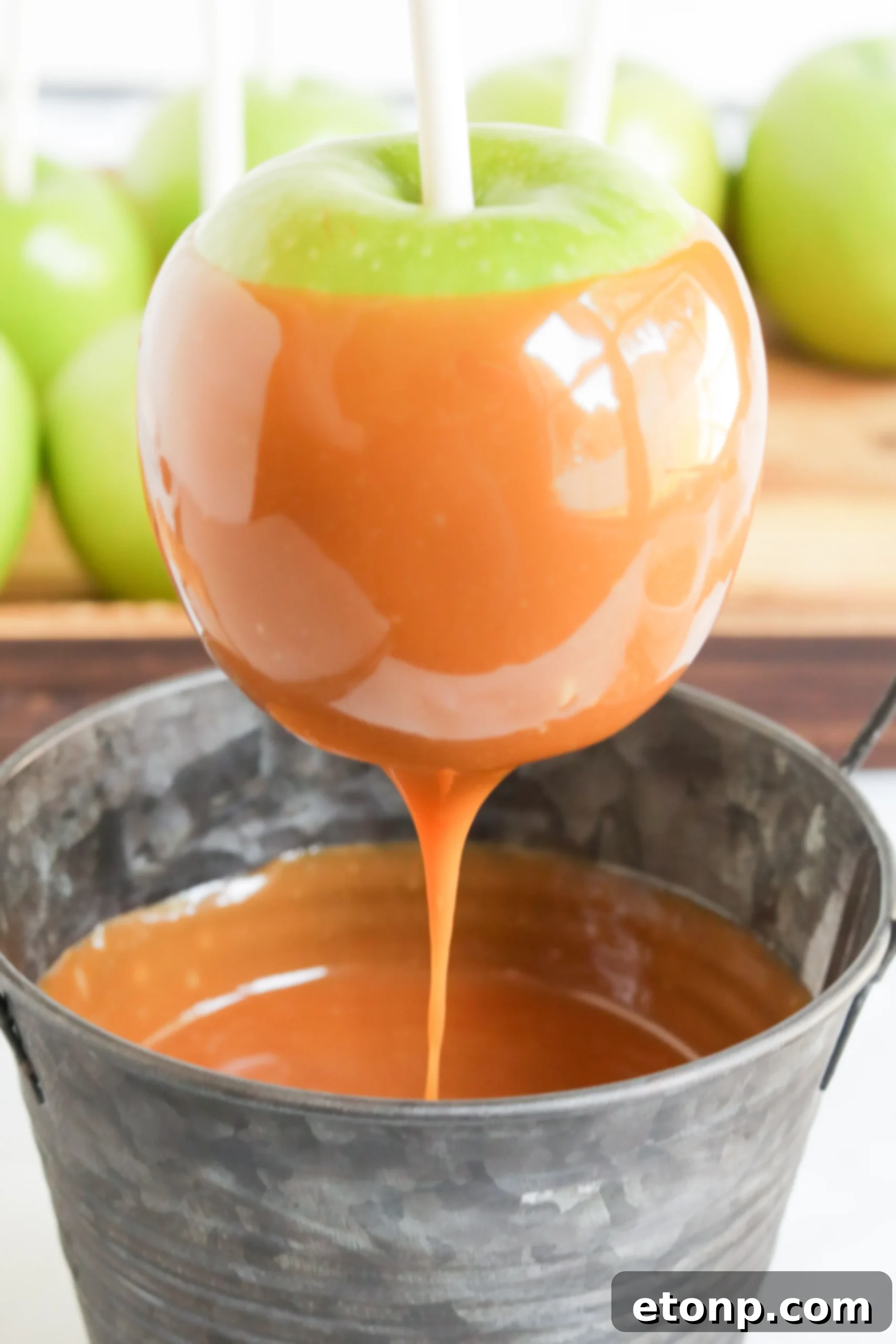 Three caramel apples neatly arranged on a wooden surface, highlighting their homemade charm