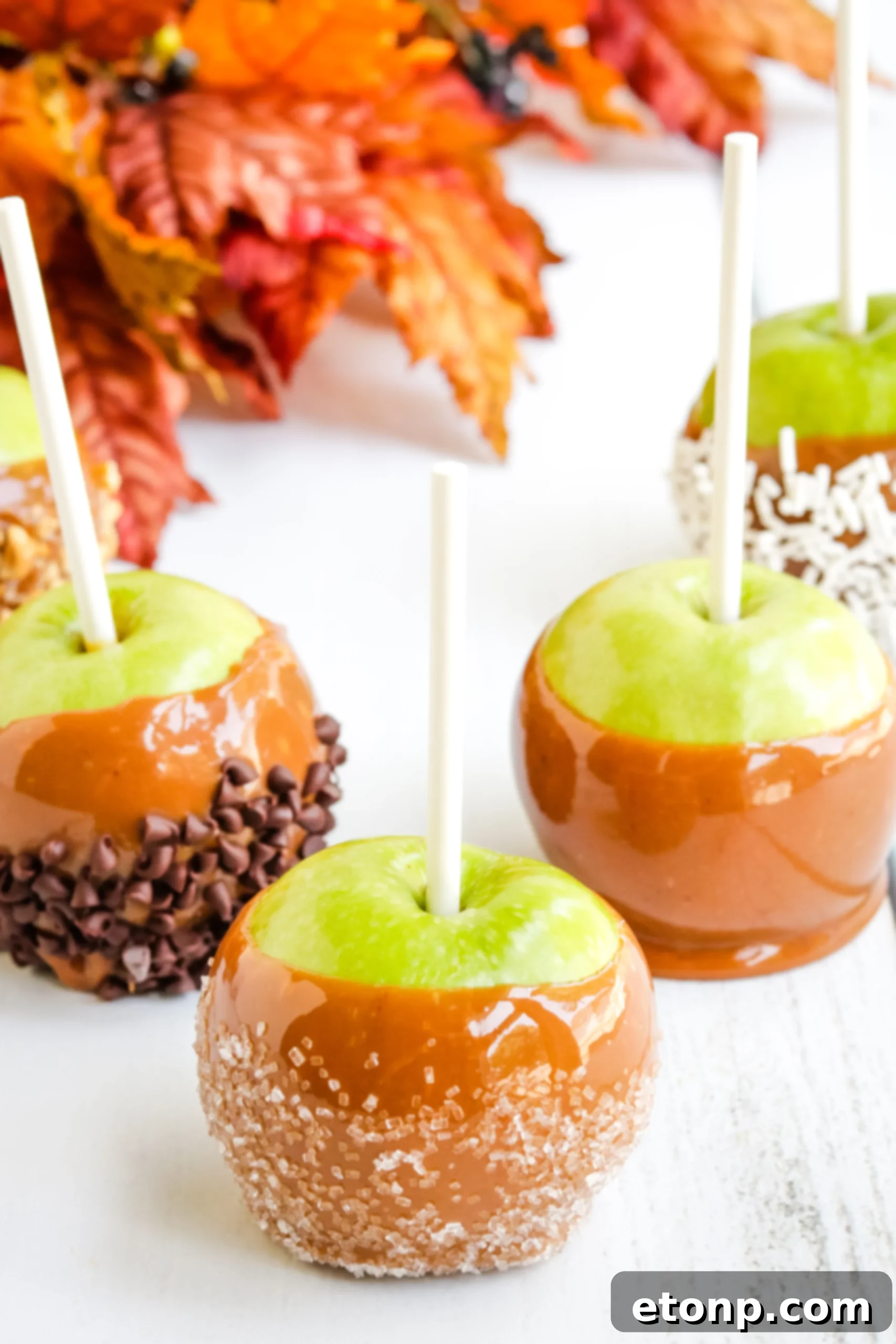A close-up of a caramel apple being dipped into a rich, golden caramel sauce