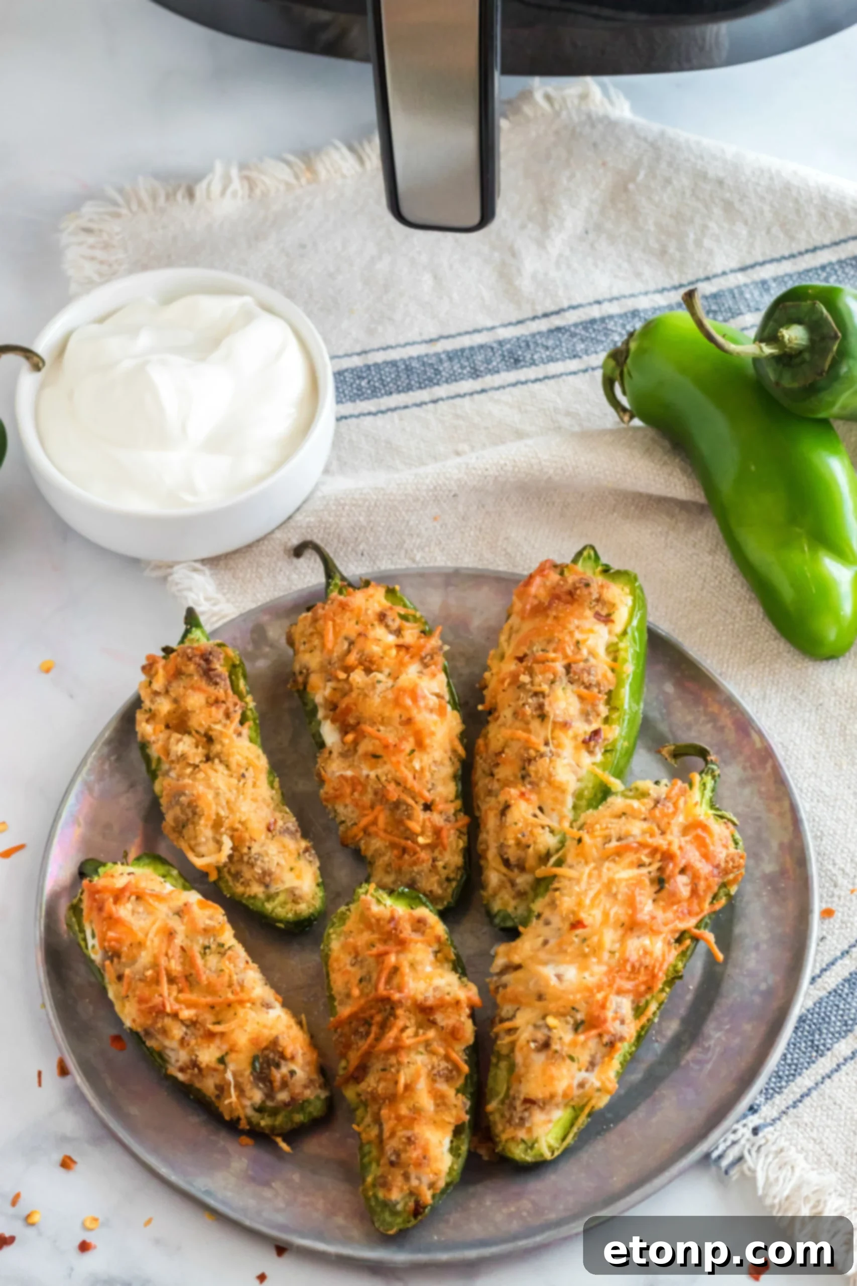 A batch of Air Fryer Jalapeno Poppers cooking inside an air fryer basket, with visible steam and crisping cheese.