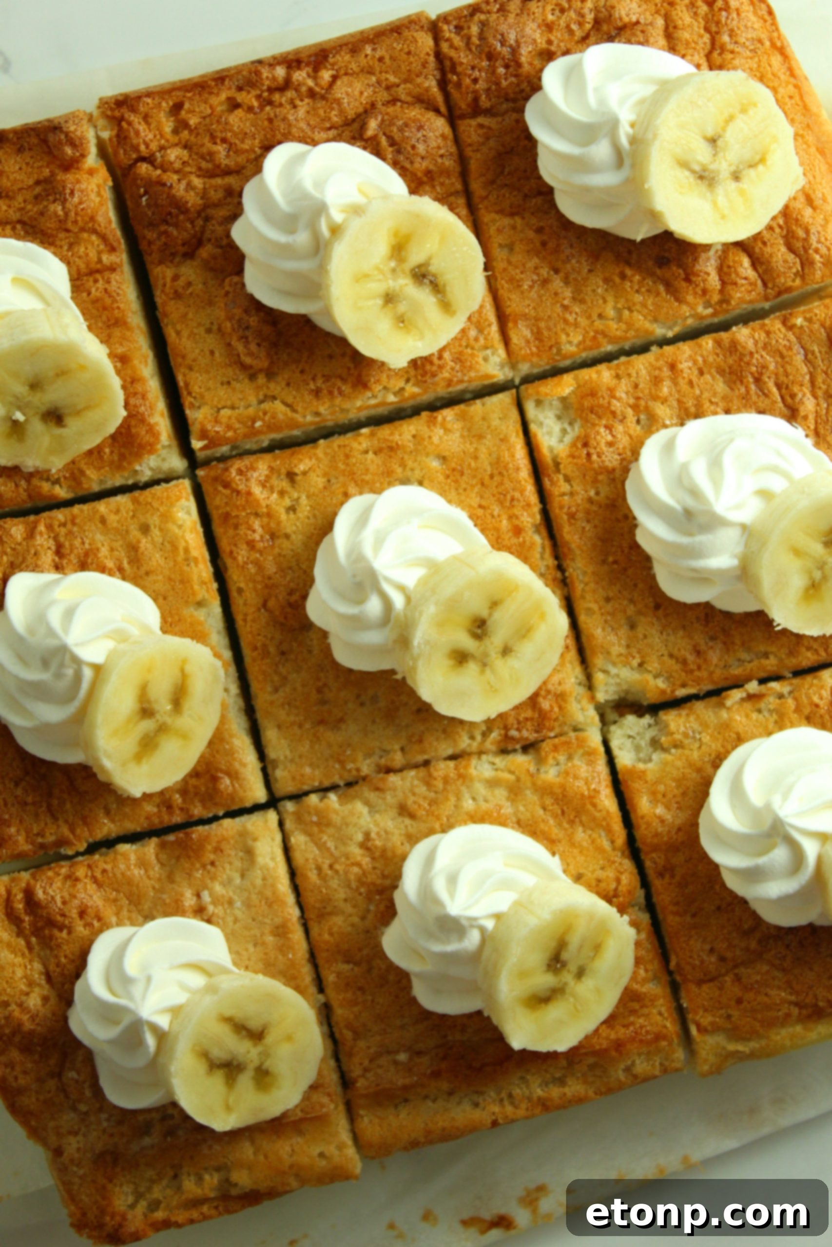 Close-up of the rich, golden-brown top of a freshly baked Banana Magic Cake, cooling in a square baking pan.