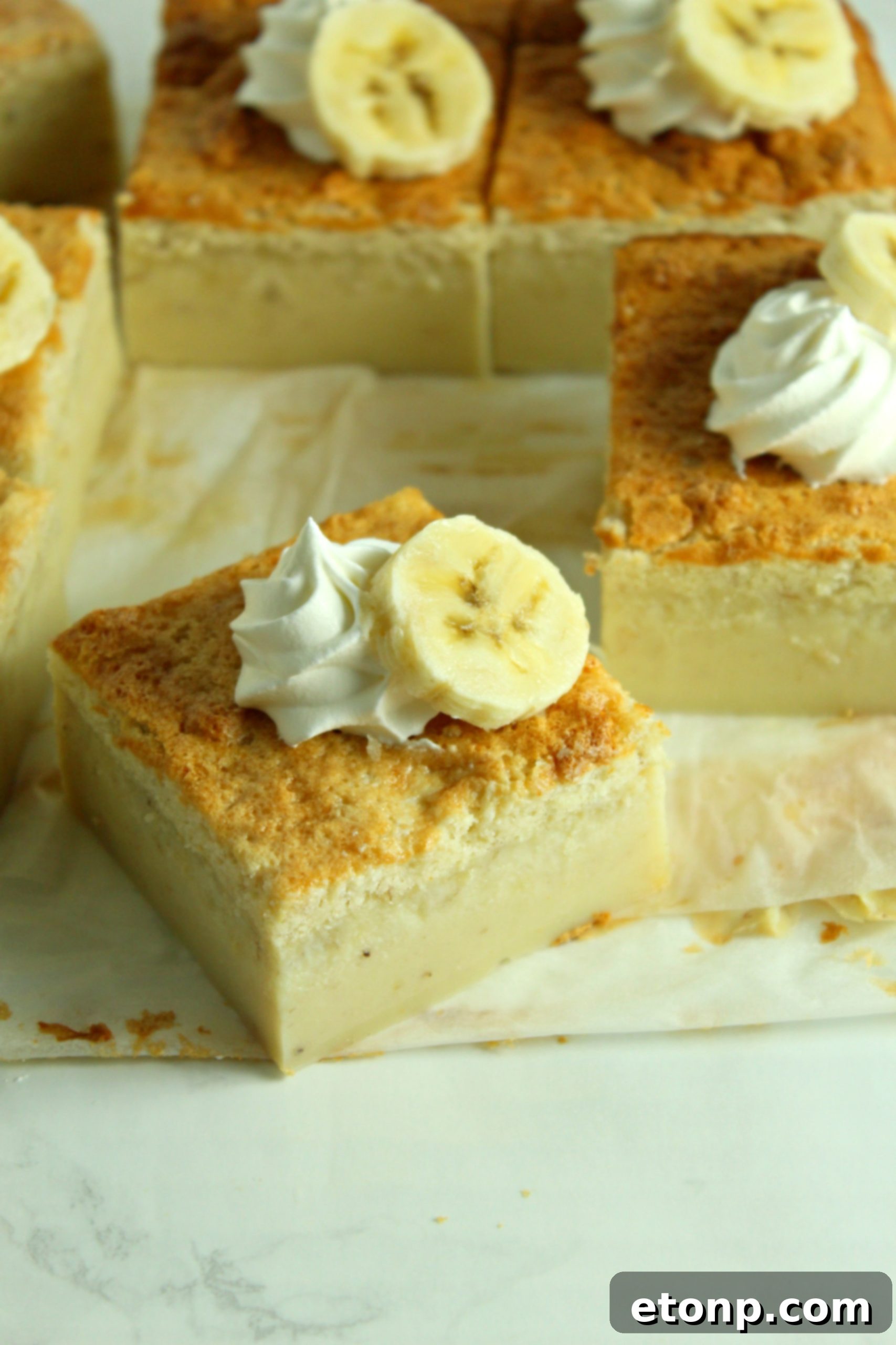 A close-up of a generous slice of Banana Magic Cake, showcasing the distinct custard, cream, and cake layers, ready for enjoyment.