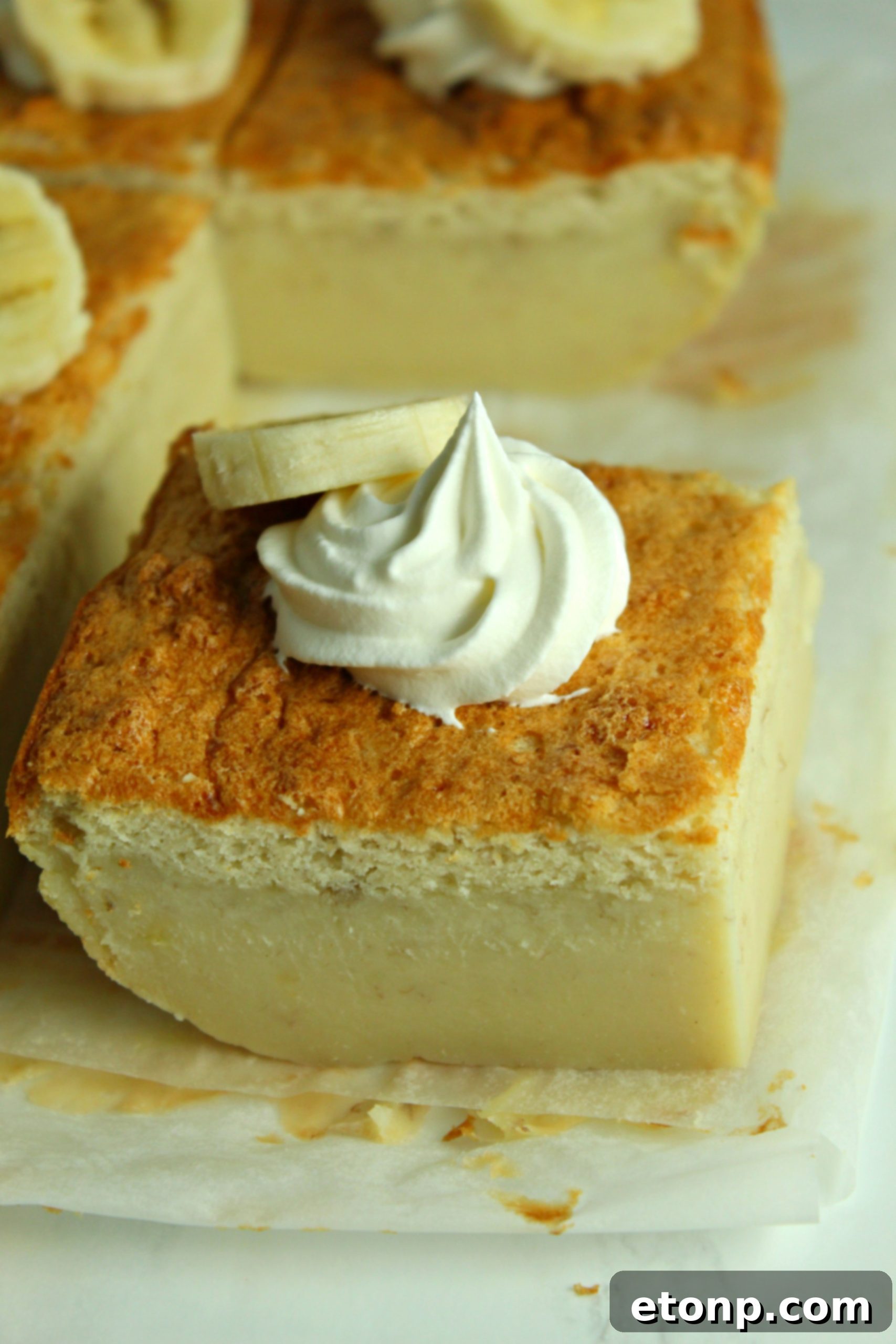 A final, enticing image of the Banana Magic Cake, perfectly presented with whipped cream and banana slices, ready to be enjoyed.
