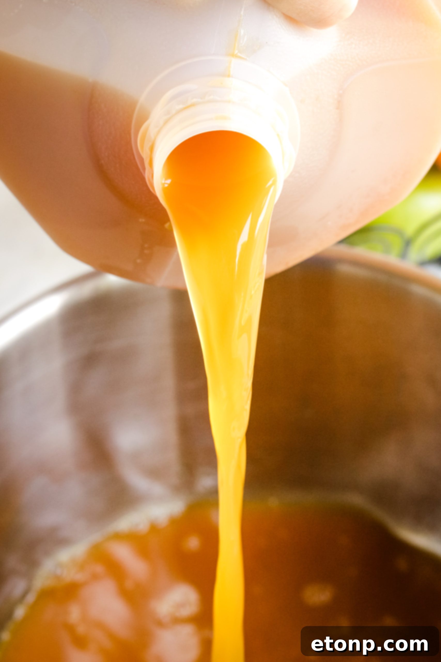 Overhead shot of a pot filled with hot mulled cider, showing apple and orange slices, cinnamon sticks, and star anise simmering.