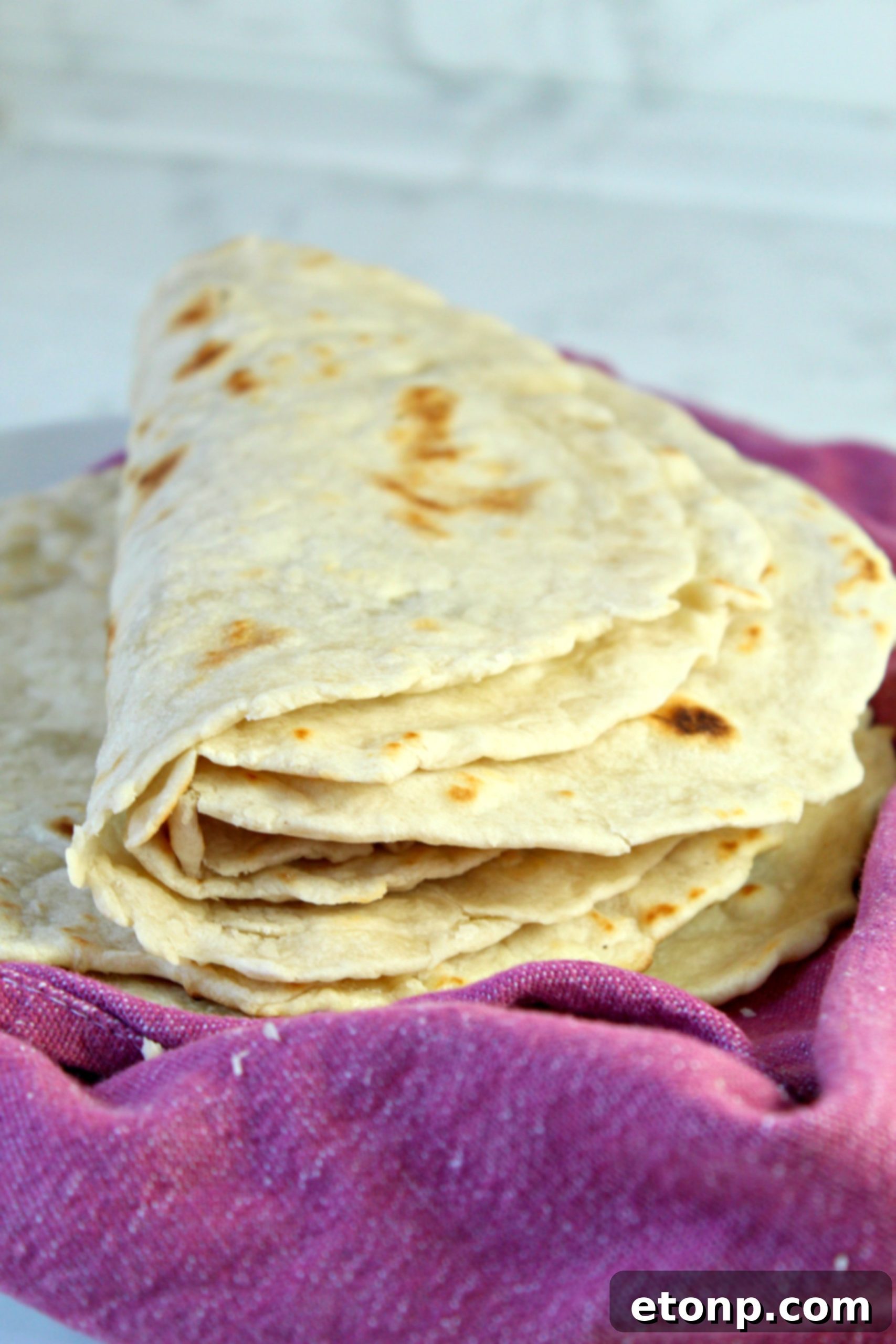 A beautifully arranged stack of warm, soft homemade flour tortillas.