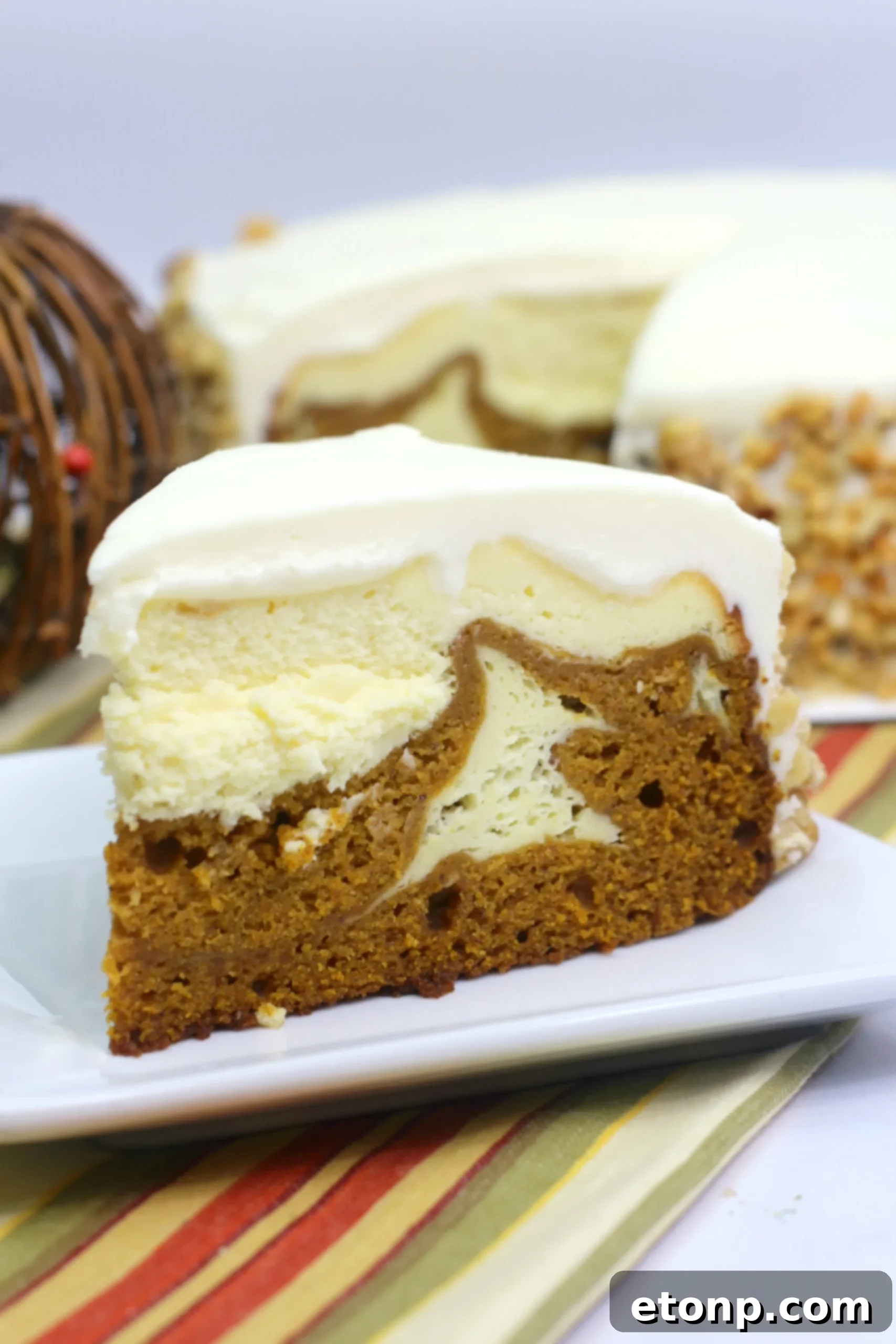 A stunning slice of Pumpkin Cake Cheesecake with creamy frosting and walnuts on top, ready to be served on a white plate