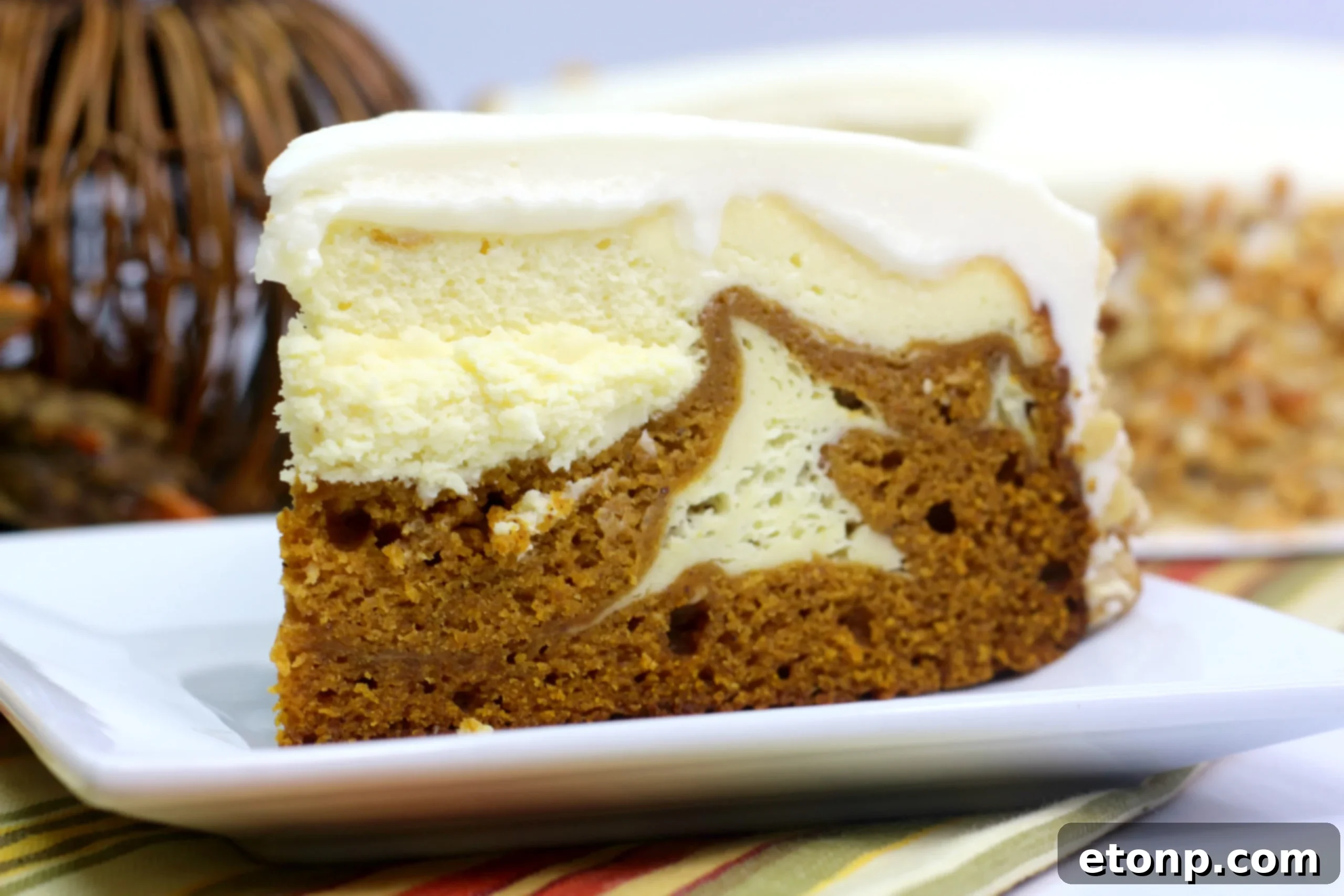 Close up of a homemade Pumpkin Cake Cheesecake slice with caramel drizzle, ready to be enjoyed as a delightful fall dessert