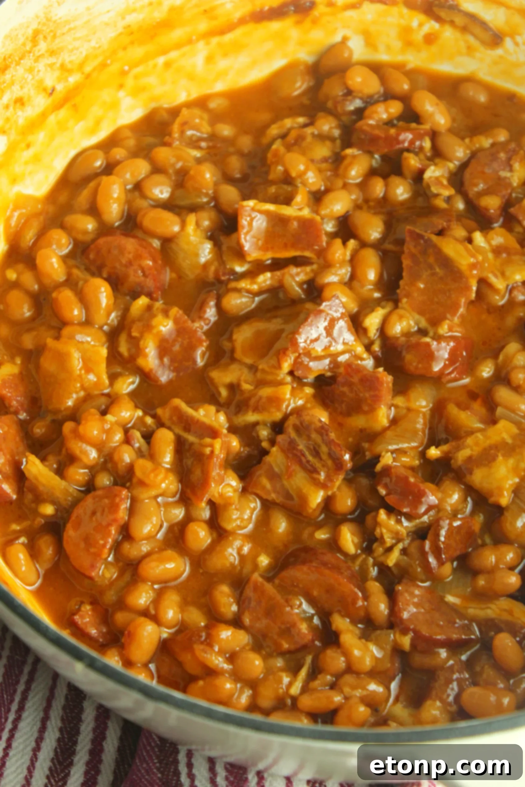 A rustic bowl of baked beans and smoked sausage, perfectly cooked, ready to be served as a comforting meal.