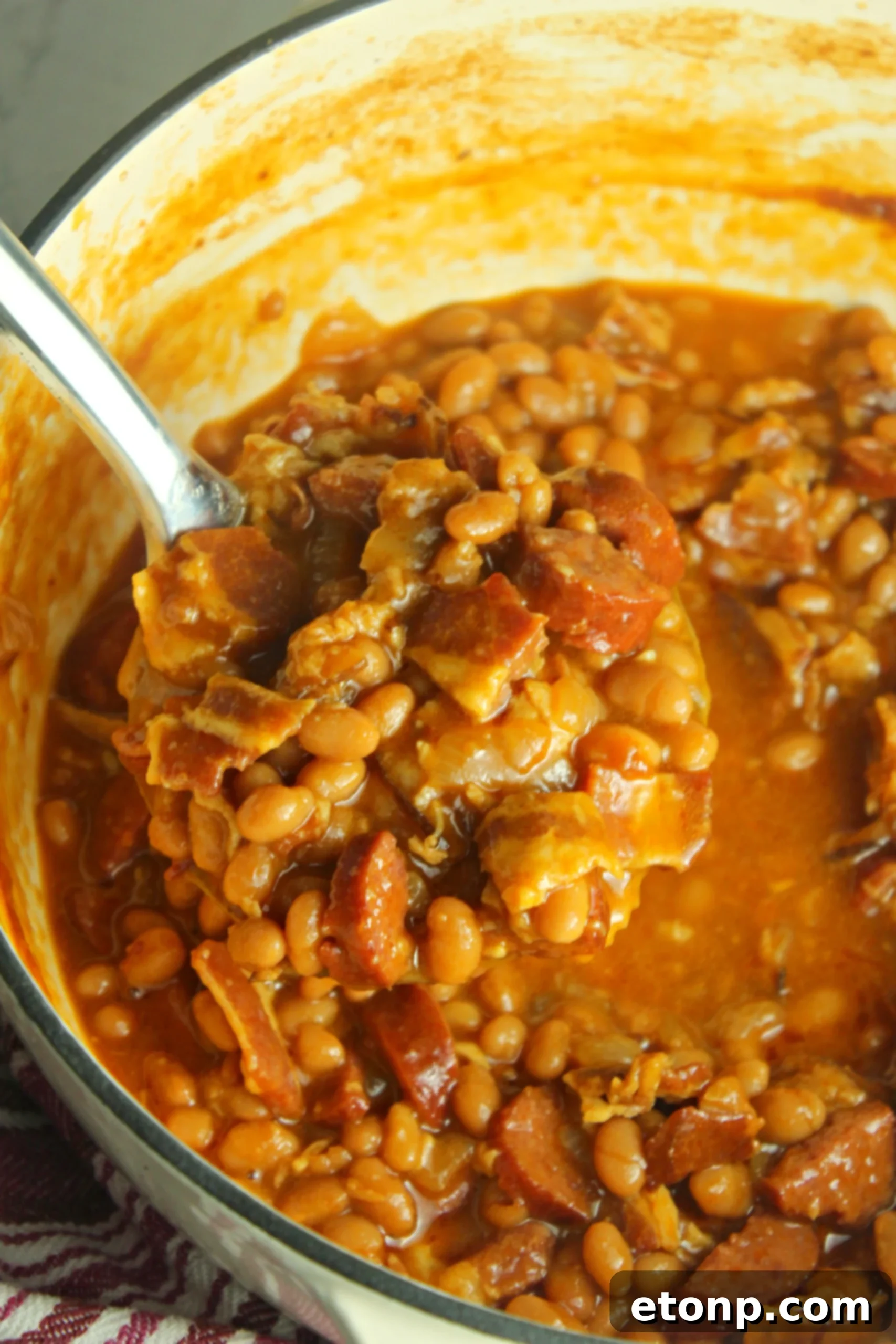 A side view of the baked beans with smoked sausage, showcasing the steam and inviting aroma of the freshly cooked dish.