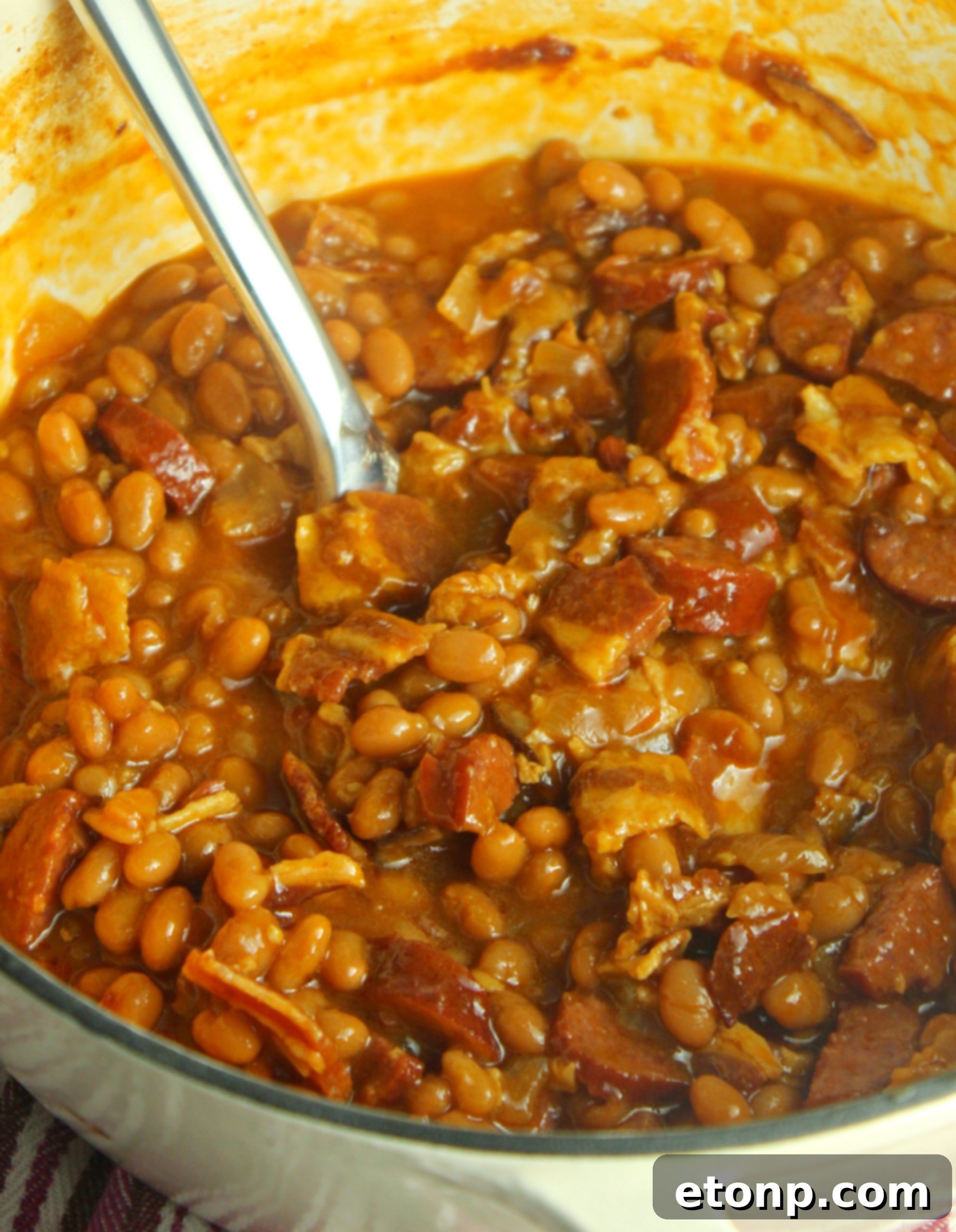 An overhead shot of a single serving of baked beans with smoked sausage, showing its inviting texture and colors.