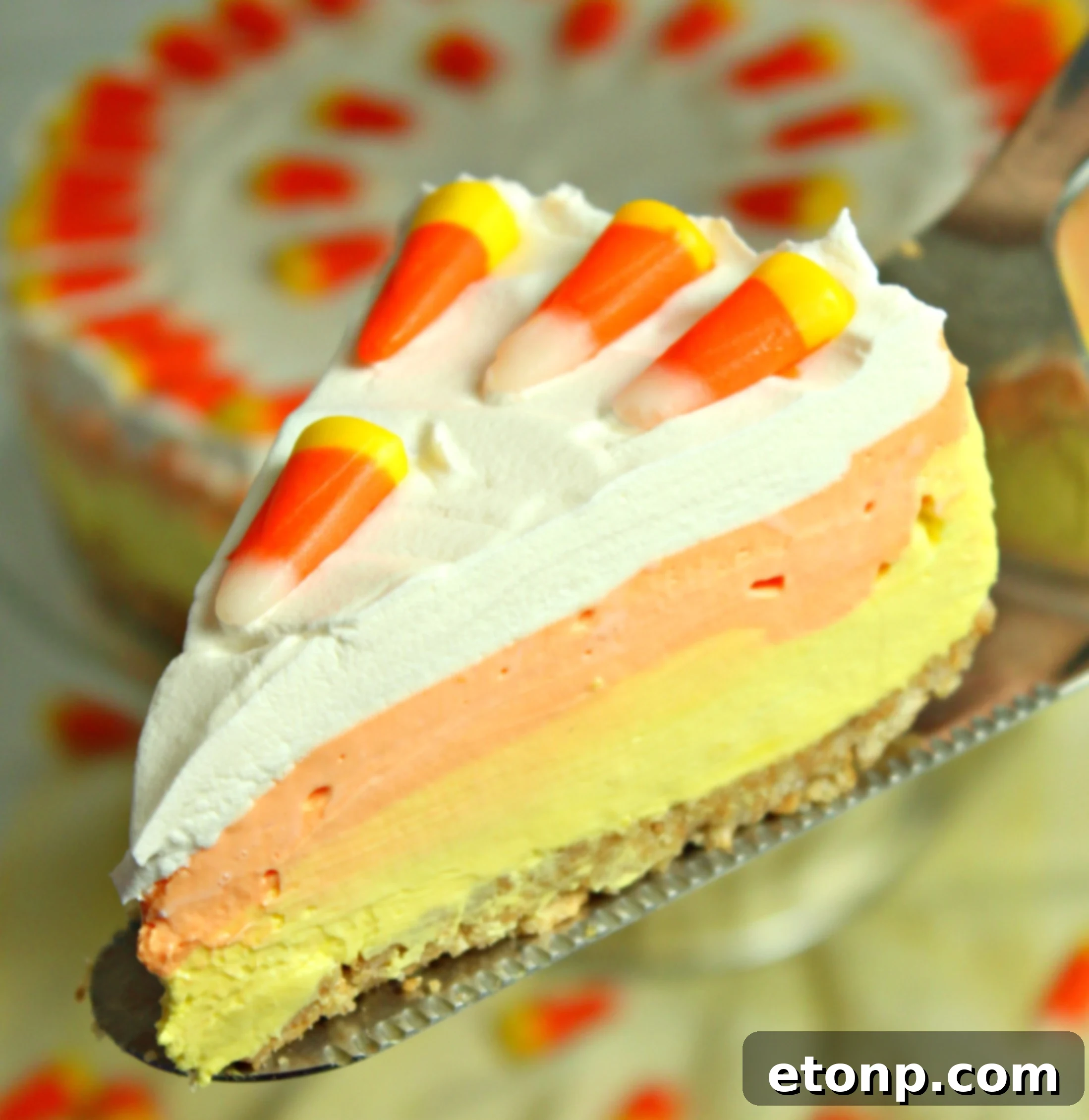 Vibrant No-Bake Candy Corn Cheesecake with distinct yellow, orange, and white layers, garnished with real candy corn