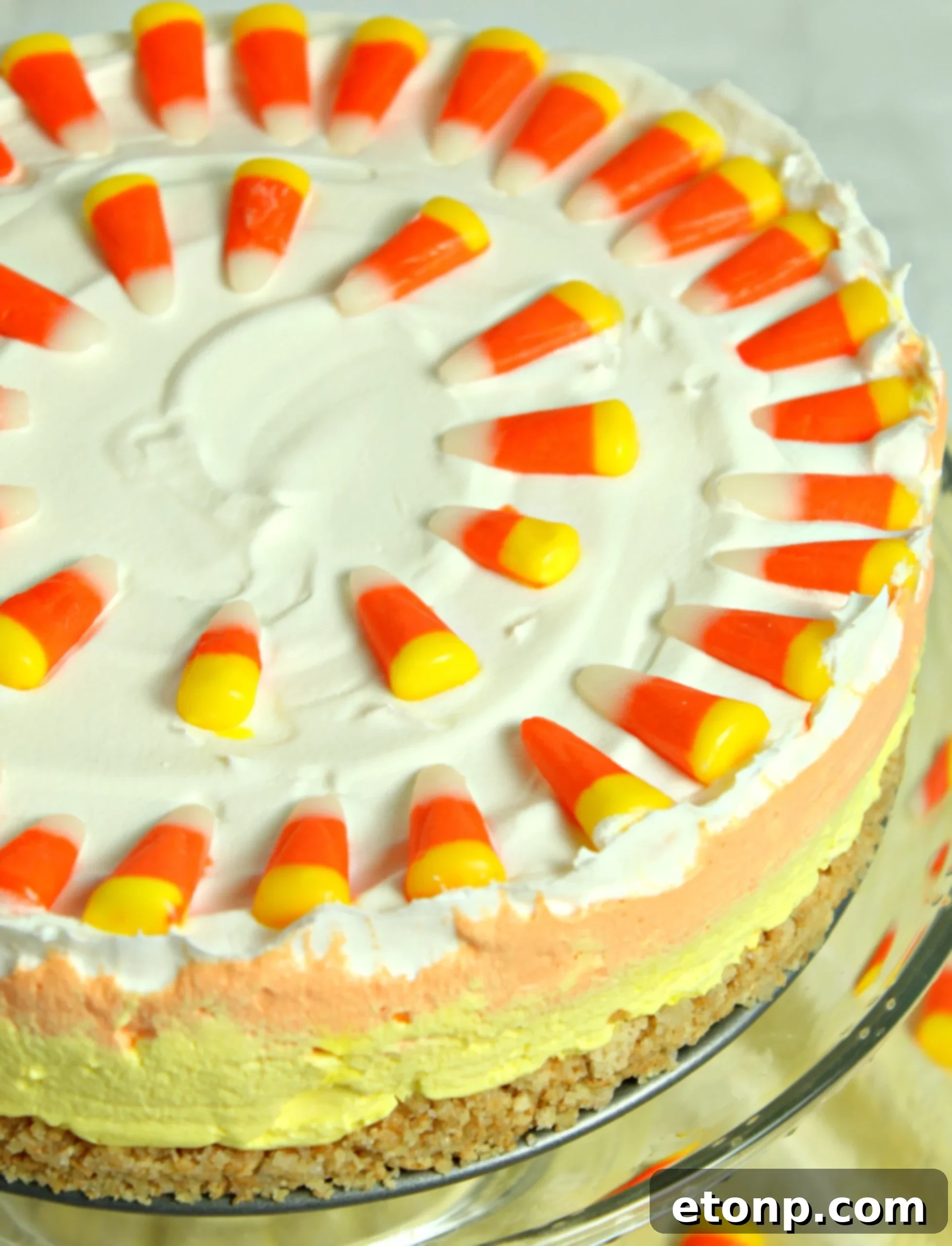The full No-Bake Candy Corn Cheesecake, showcased on a wooden surface, with its decorative candy corn topping in clear view.