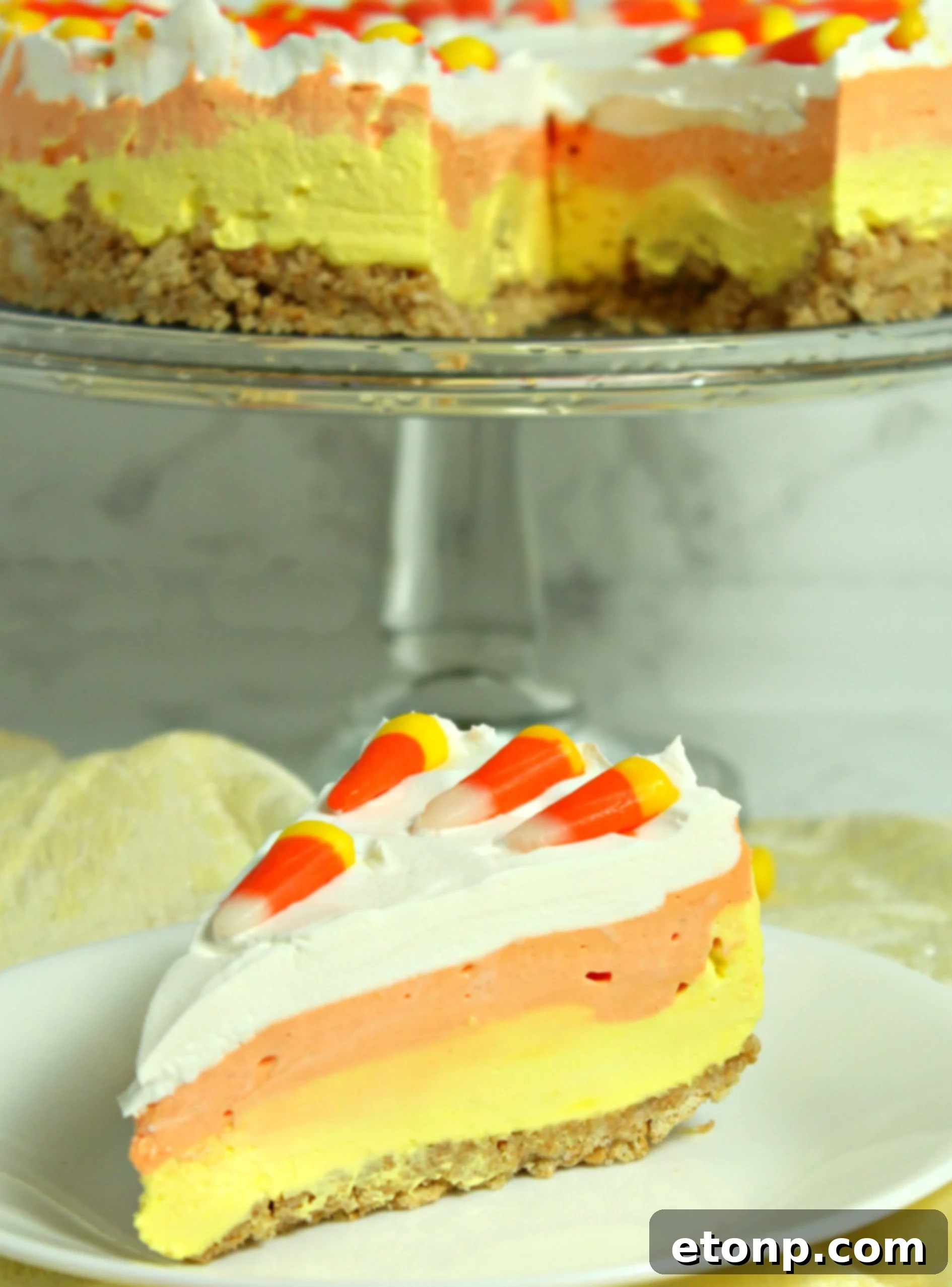 A beautifully composed shot of the No-Bake Candy Corn Cheesecake, ready to be served, showcasing its impressive height and layers.