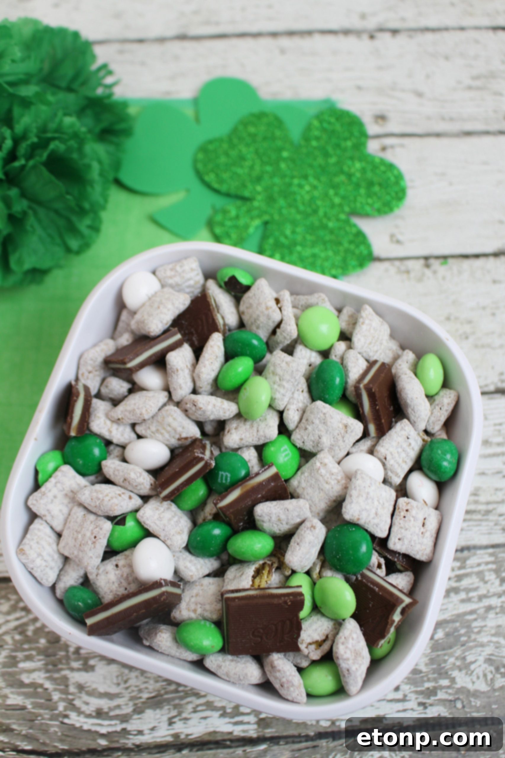 A large batch of Andes Mint Muddy Buddies spread out on wax paper on a baking sheet to cool, displaying their uniform coating.