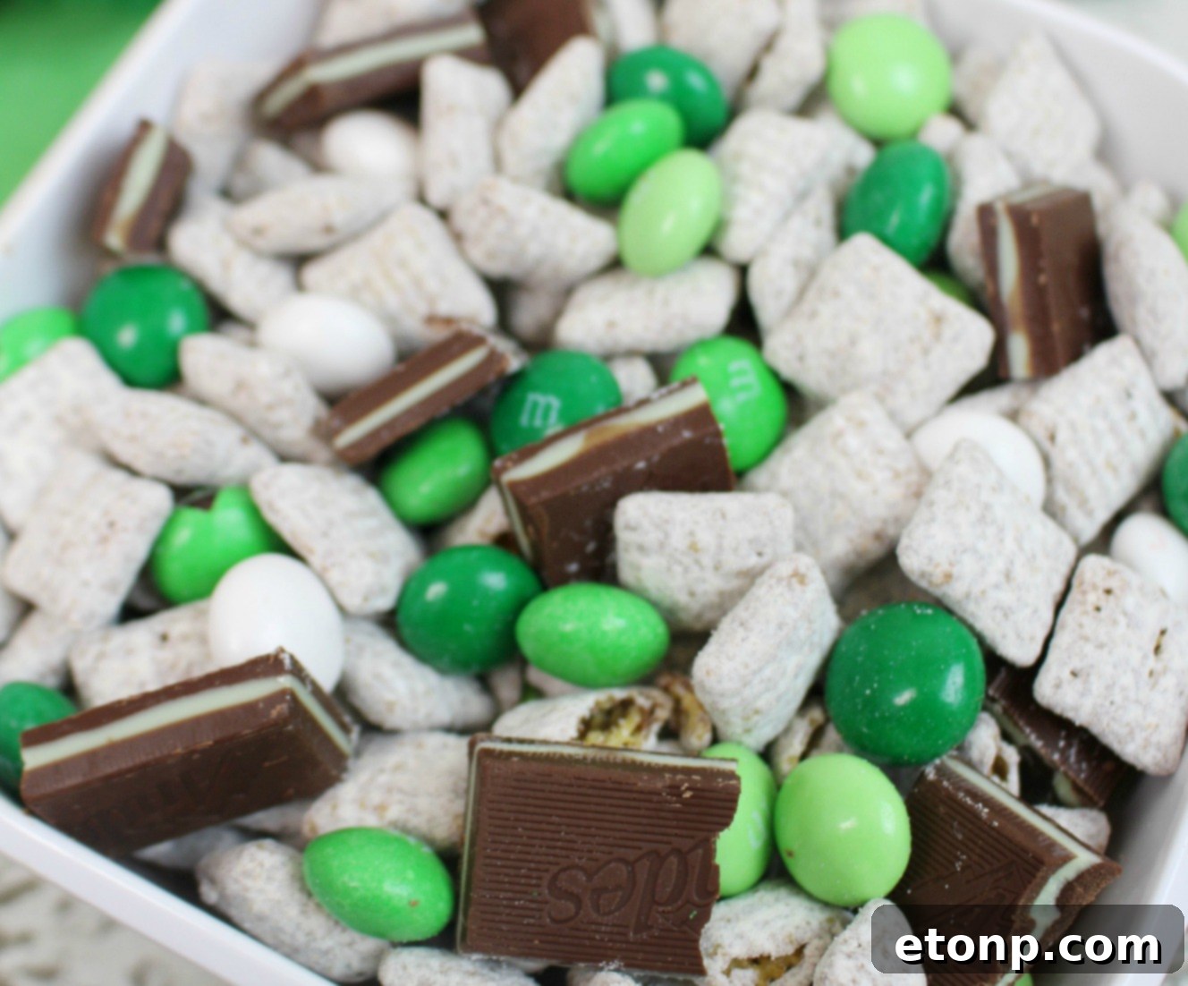A scoop of Andes Mint Muddy Buddies being lifted from a bowl, showing the delightful texture and ingredients.