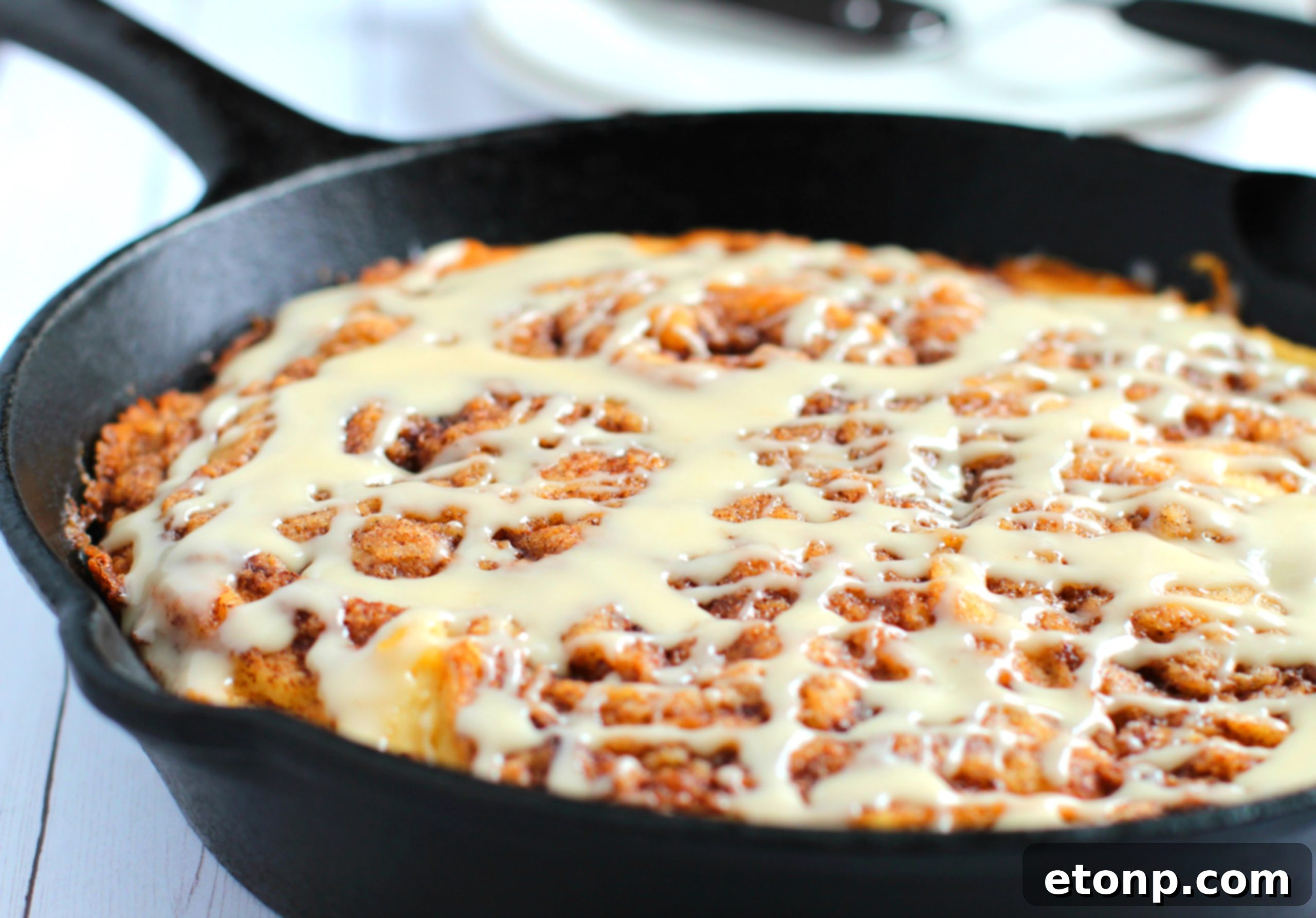 Warm Cinnamon Swirl Skillet Delight 4 A slice of Gluten-Free Cinnamon Roll Skillet Cake showing its soft interior and abundant vanilla icing.