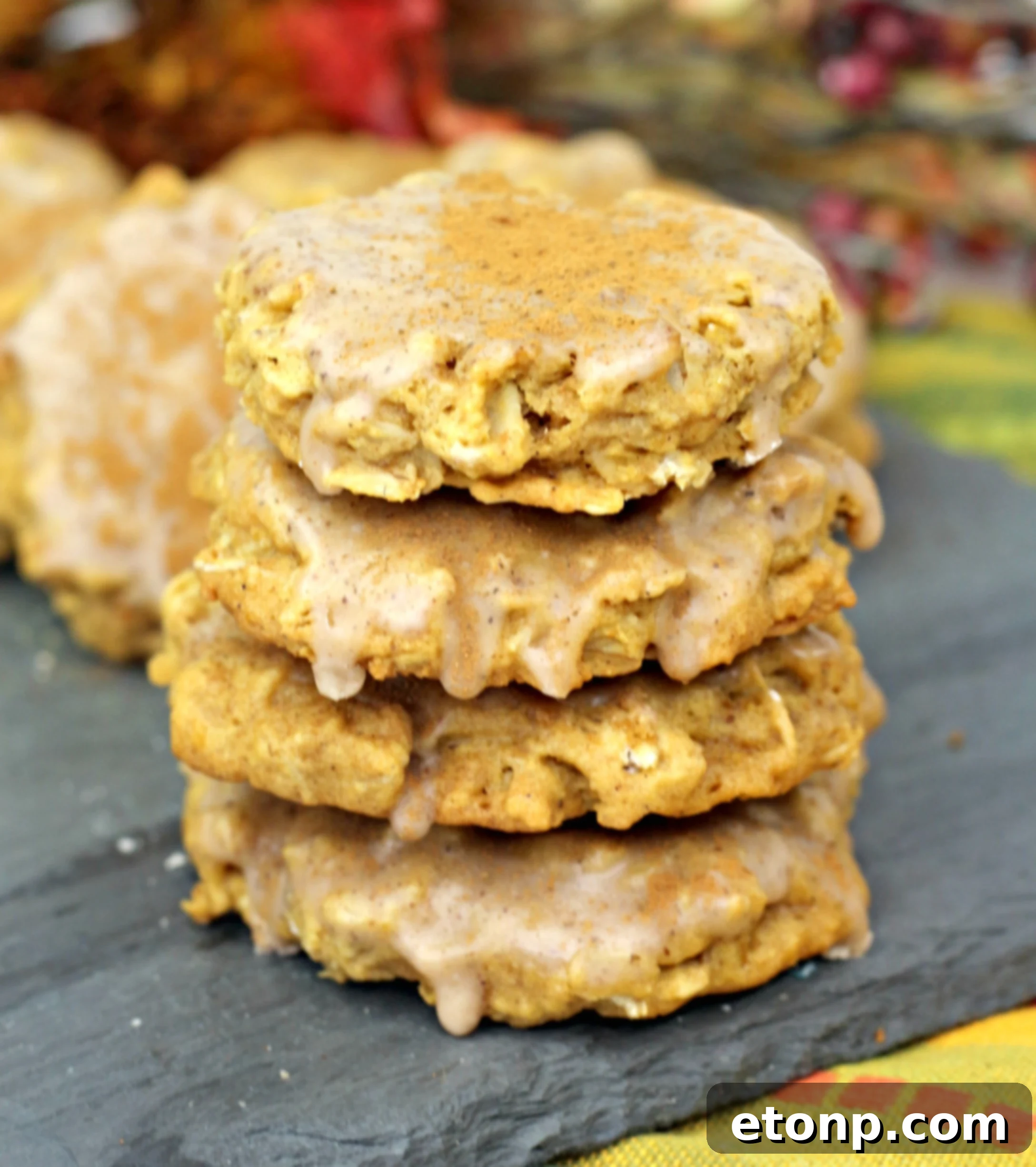 Several freshly baked Iced Pumpkin Oatmeal Cookies arranged artfully on a cooling rack, some still steaming.