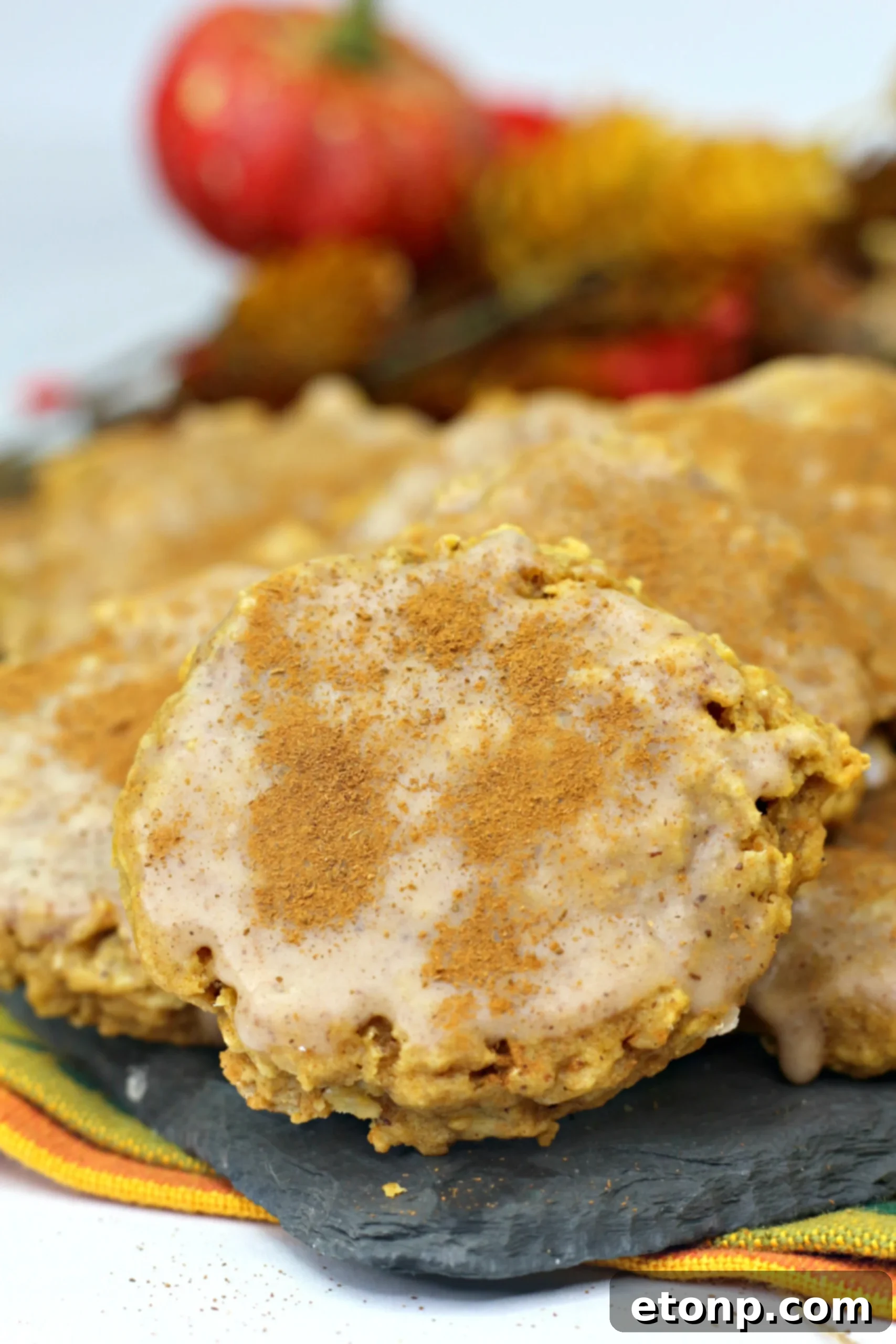 A close-up of a single Iced Pumpkin Oatmeal Cookie, showcasing the texture of the oats and the smooth, swirled icing.