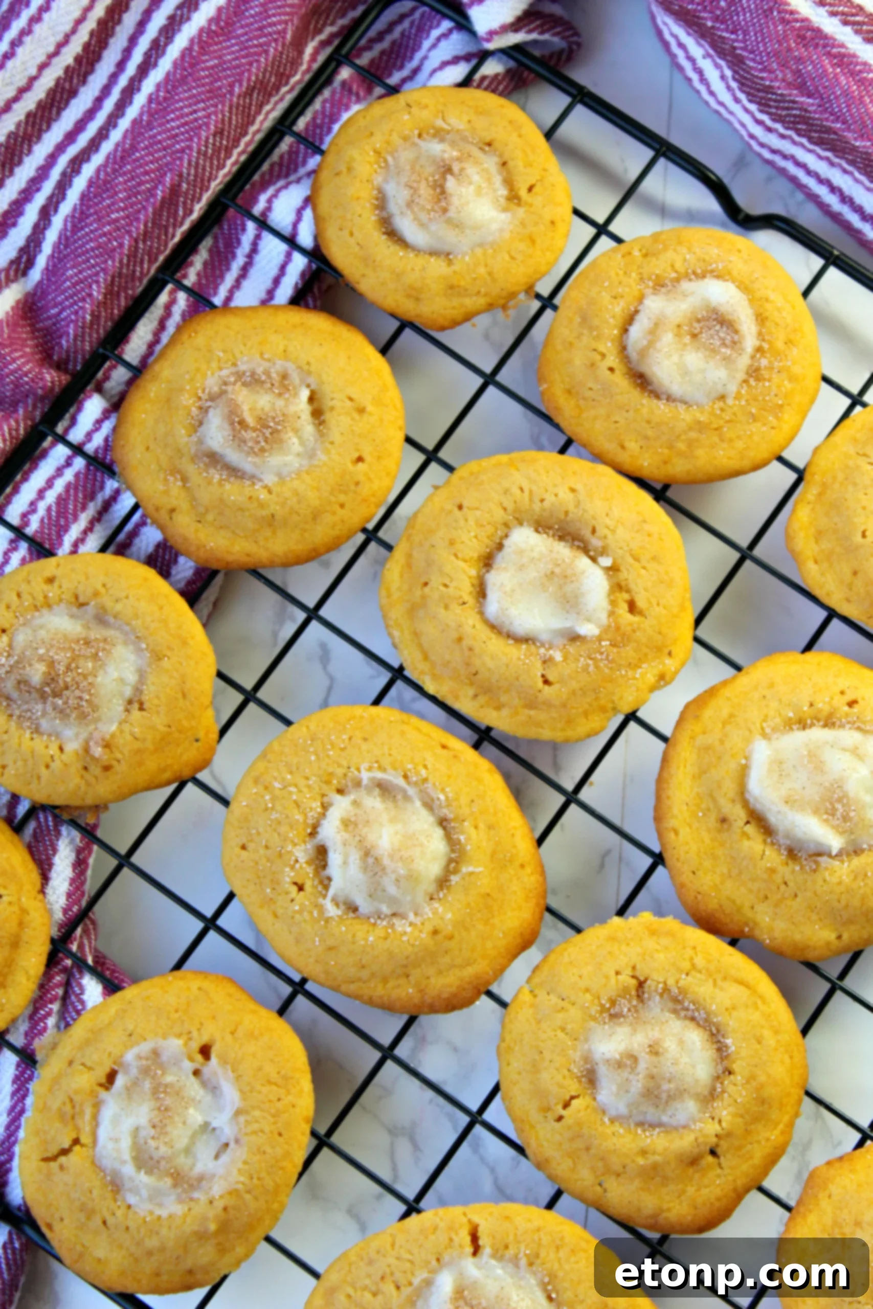 Pumpkin cheesecake thumbprint cookies arranged on a cooling rack, showcasing their golden edges