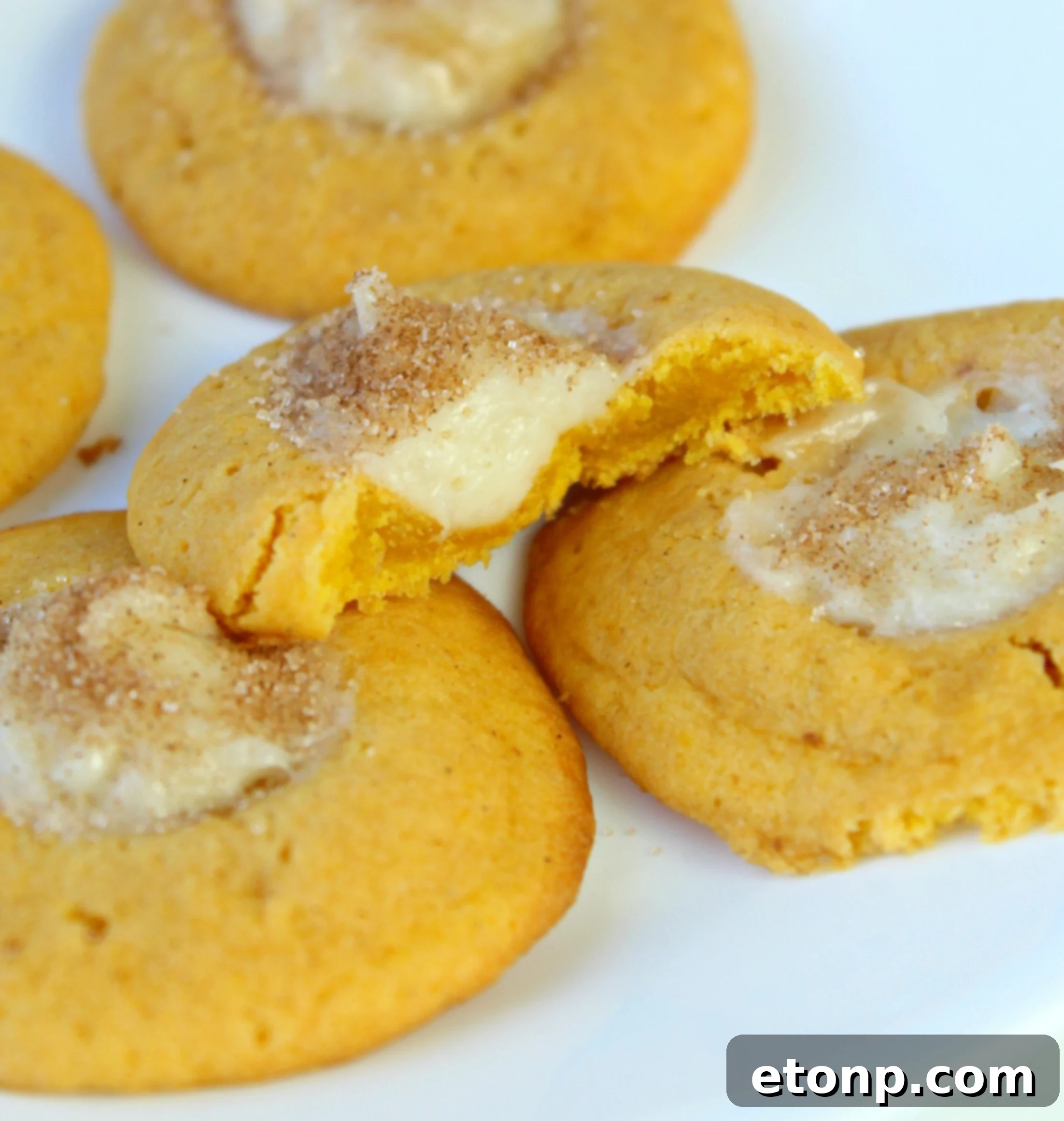 Several pumpkin cheesecake thumbprint cookies stacked on a plate, ready to be enjoyed or gifted