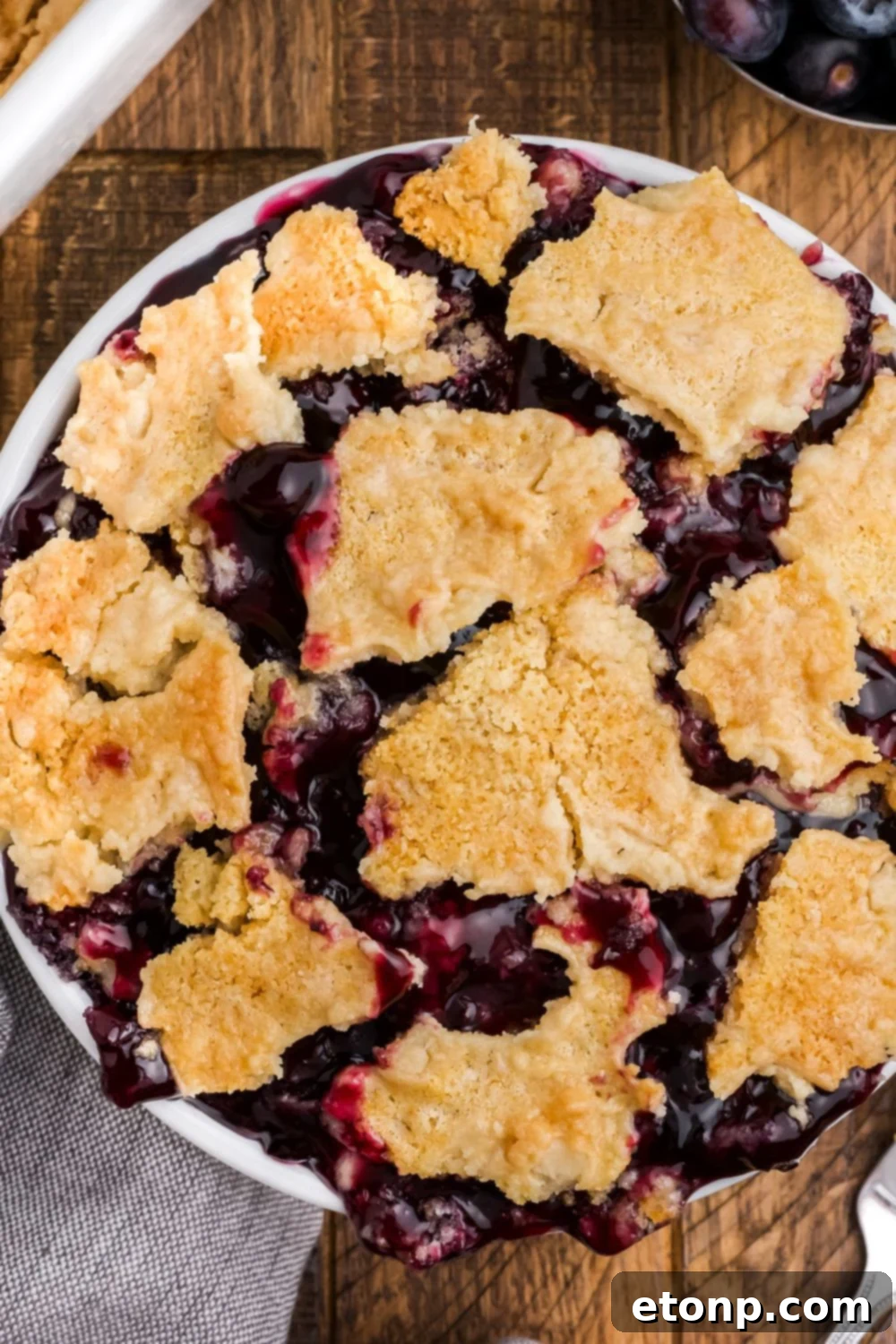close up of Blueberry Dump Cake in a white bowl on table on a wooden table