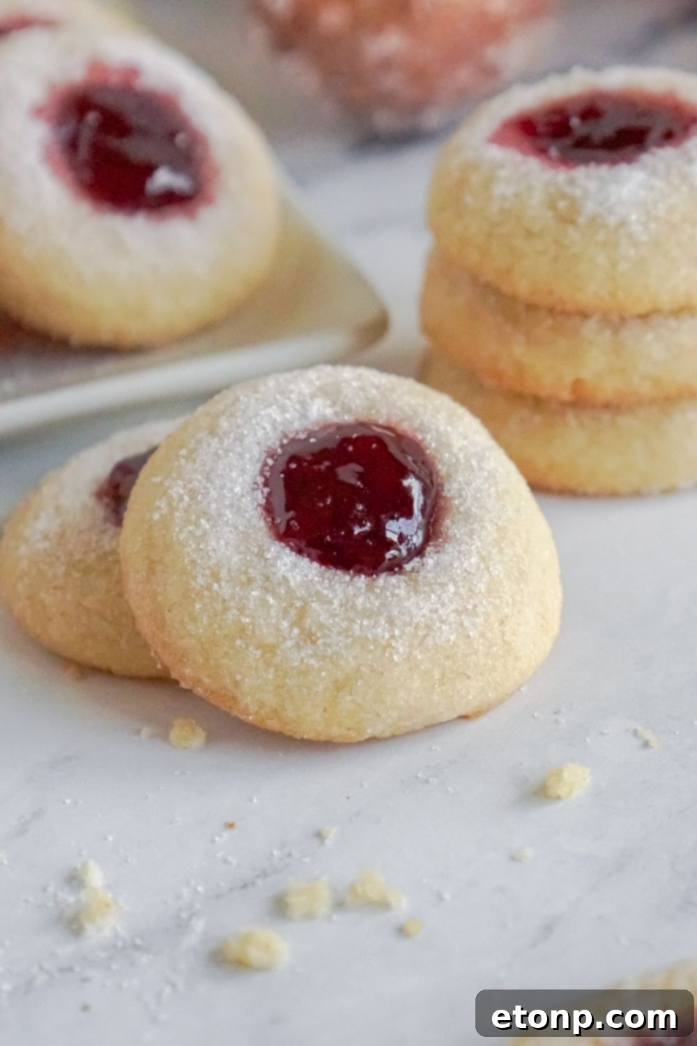 Raspberry Thumbprint Cookies displayed around a table, with some cookies stacked.