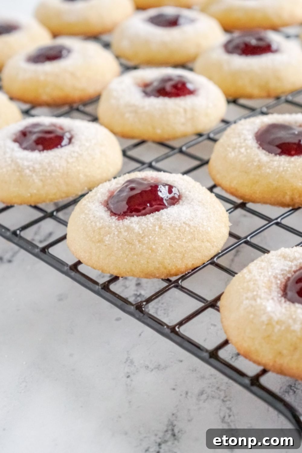 Raspberry Thumbprint Cookies on a cooling rack, showcasing their side profile.