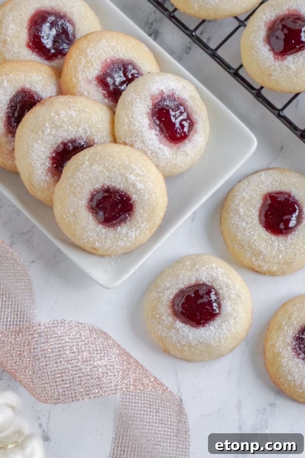 Raspberry Thumbprint Cookies arranged on a rectangle tray with a ribbon.