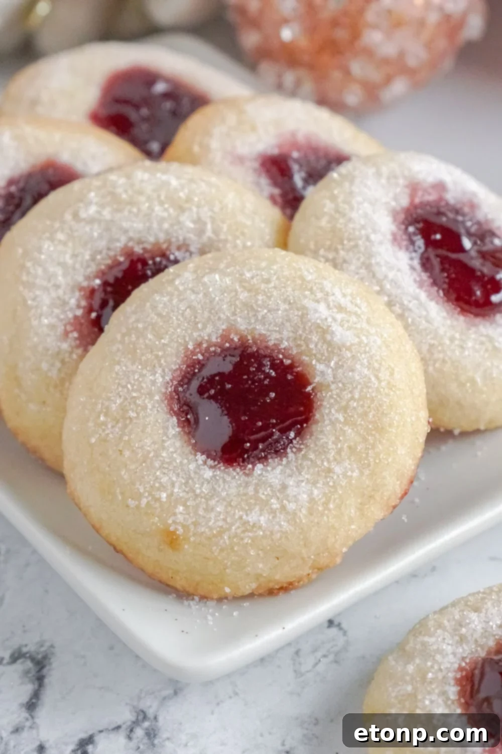 Raspberry Thumbprint Cookies displayed on a platter against a marble backdrop.