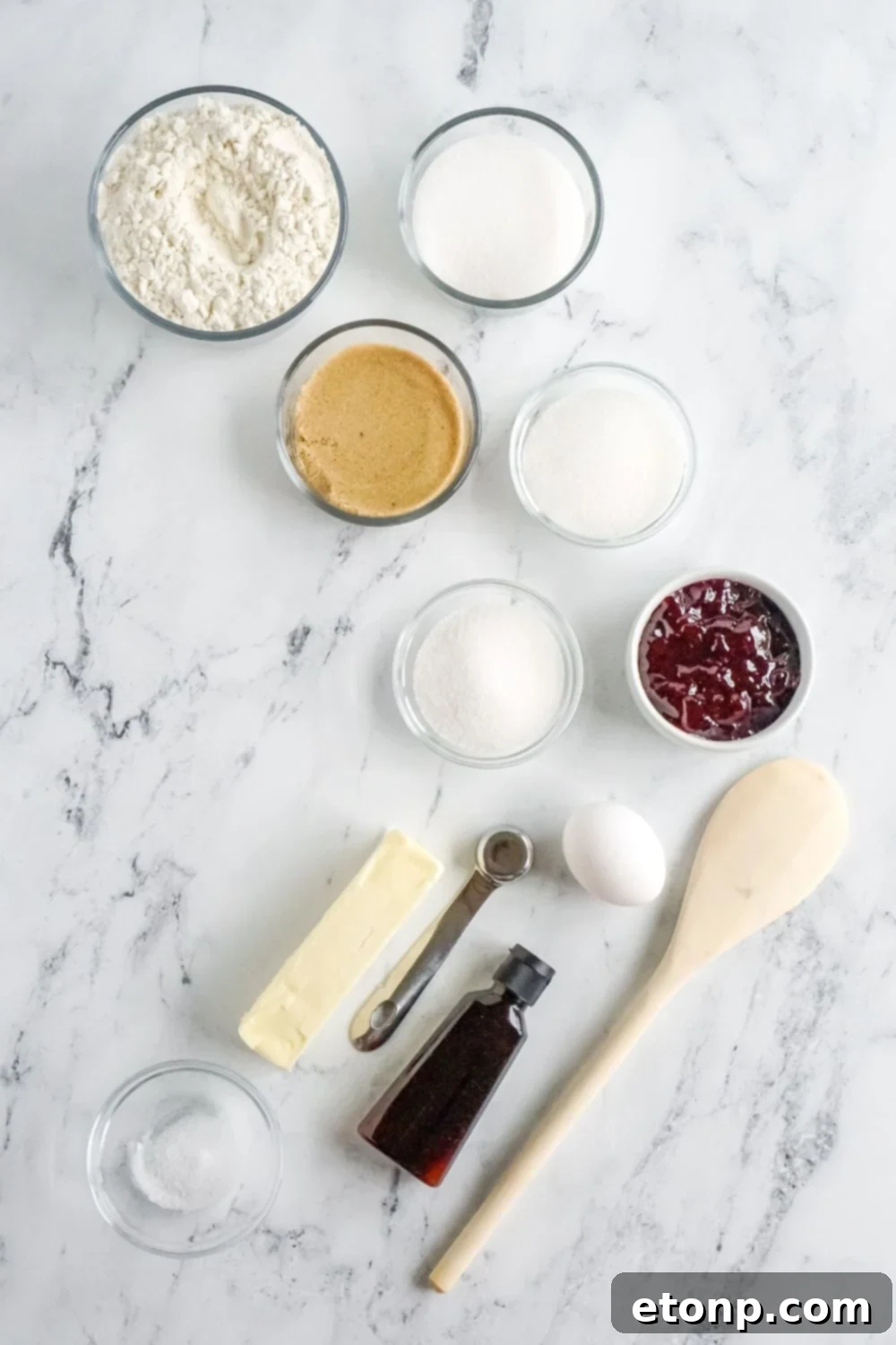 All the fresh ingredients for making Raspberry Thumbprint Cookies set out on a marble counter.