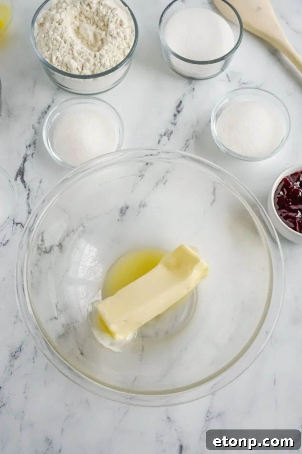 Melted butter in a clear glass bowl on a marble countertop.