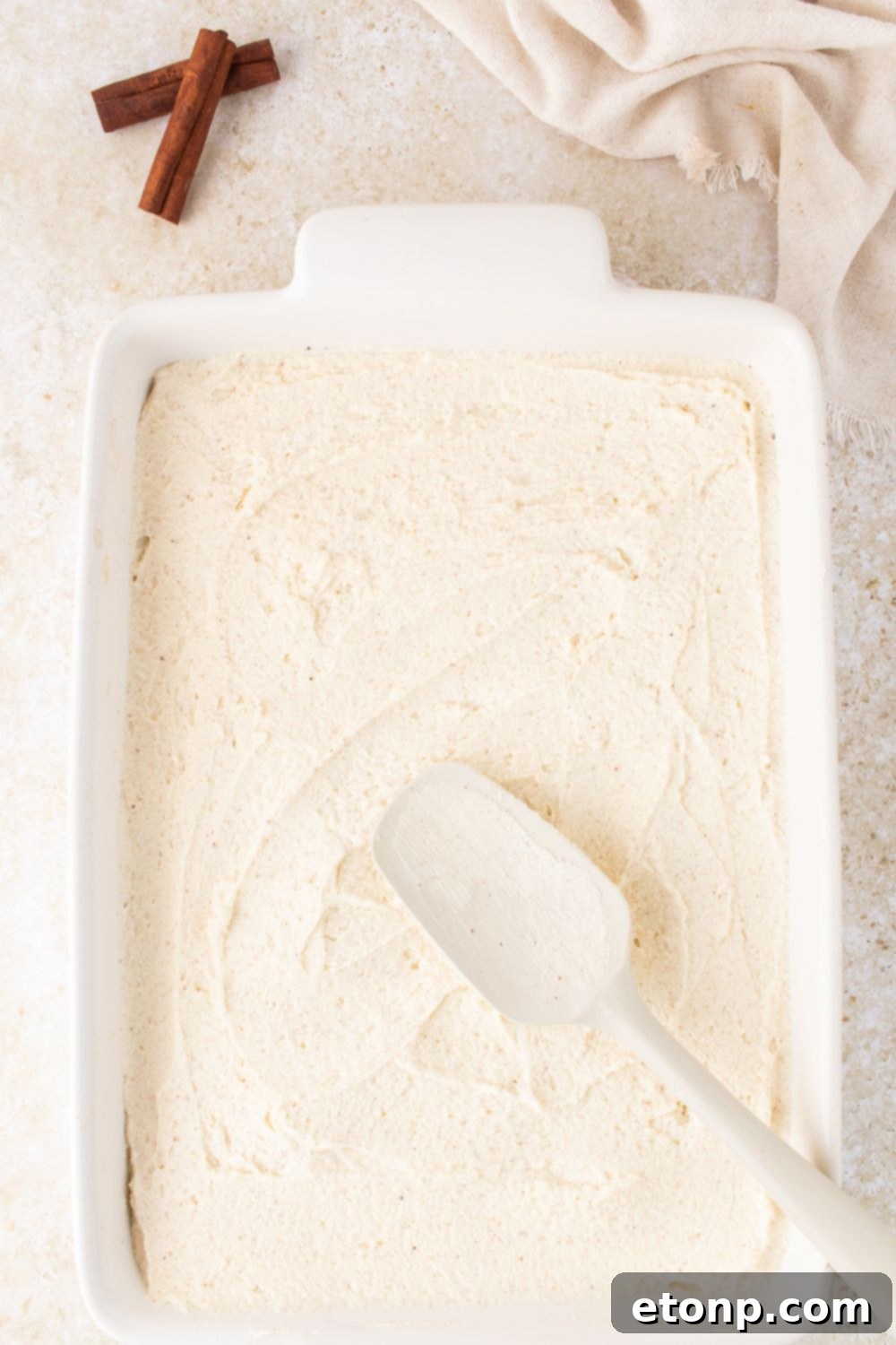 Eggnog Tiramisu: A Festive Holiday Treat 11 Eggnog Tiramisu being assembled with a spatula spreading around the creamy topping