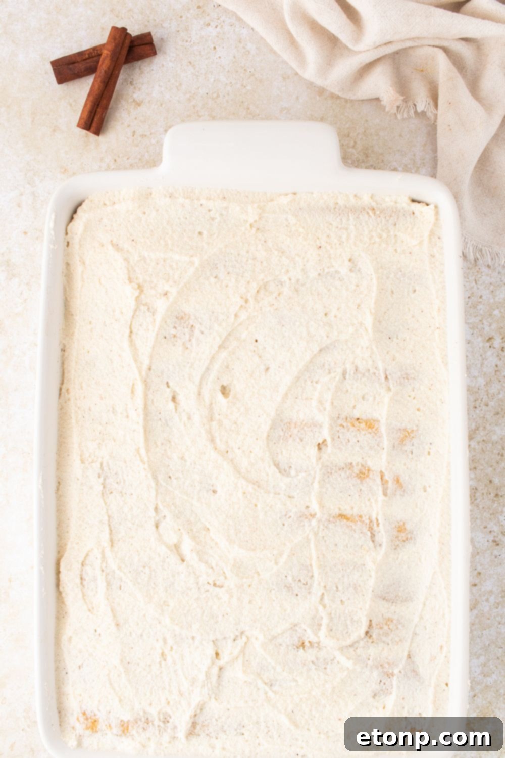 Eggnog Tiramisu: A Festive Holiday Treat 13 Creamy topping spread on a casserole dish on table