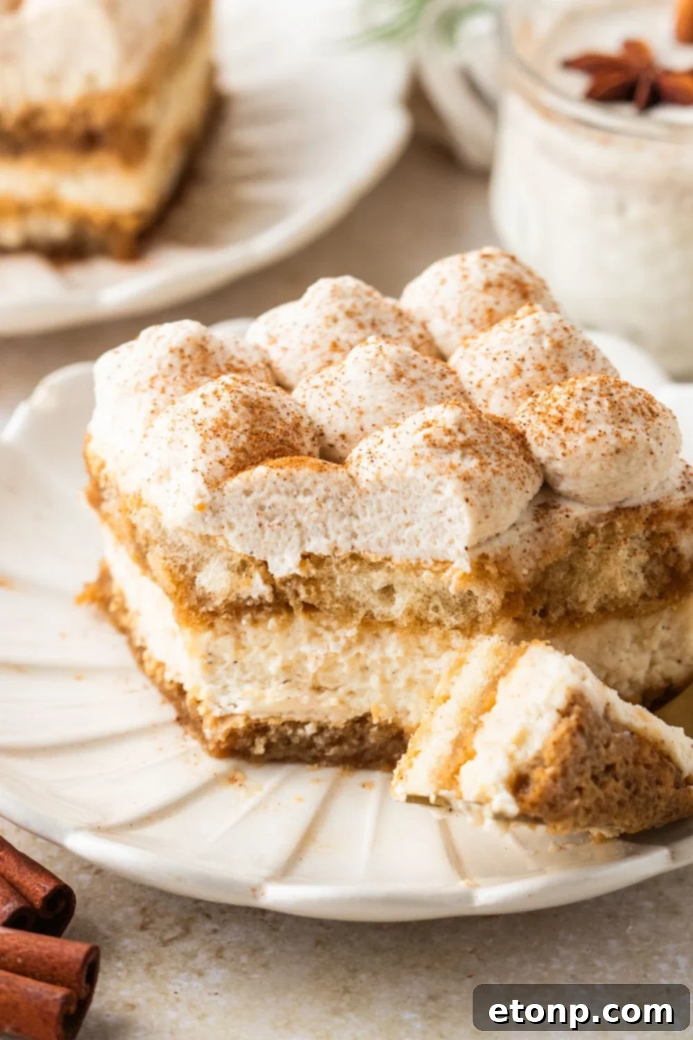 Eggnog Tiramisu: A Festive Holiday Treat 21 Eggnog Tiramisu on a plate with a bite on the fork with a plate with another slice of eggnog dessert