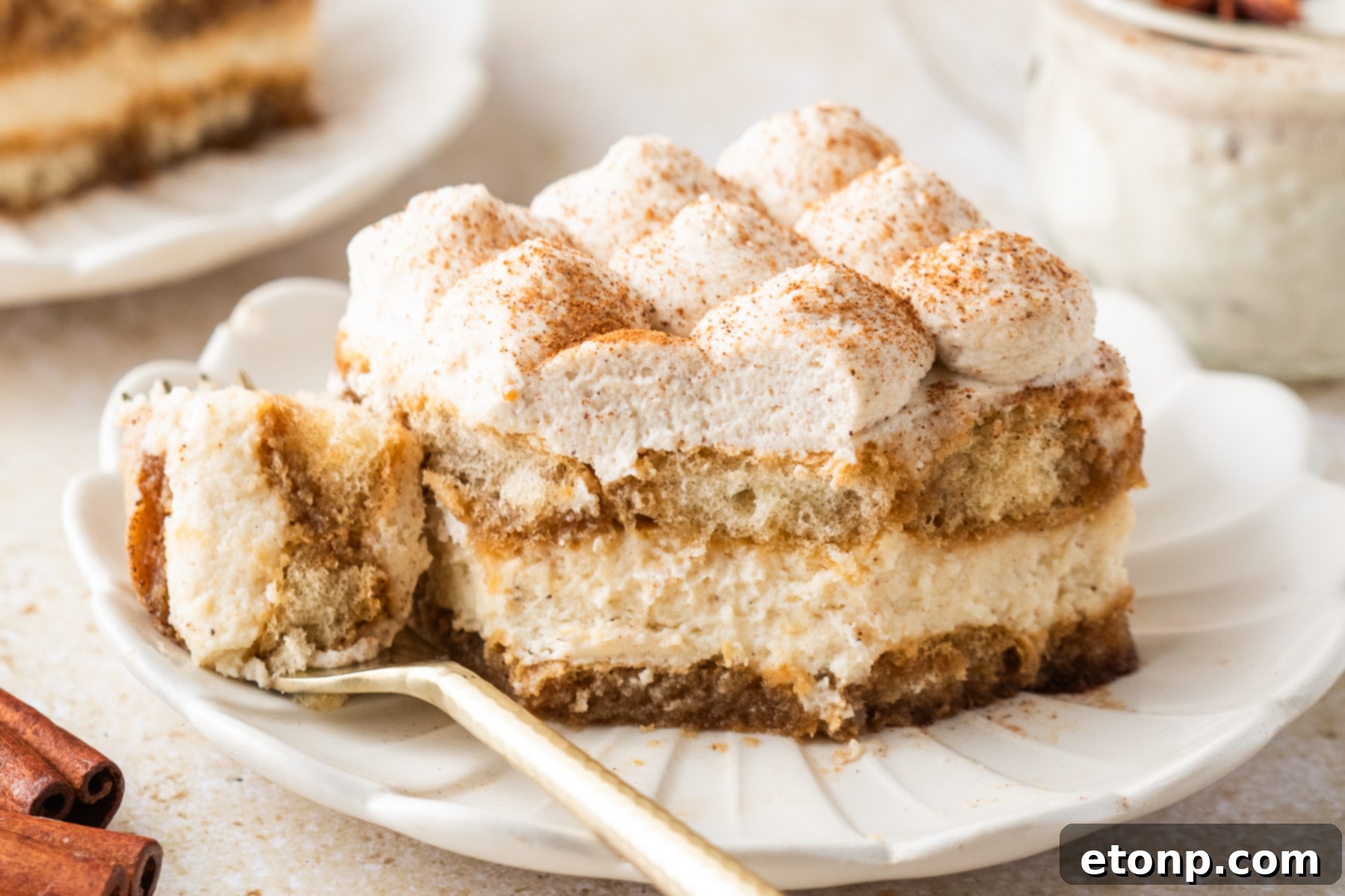 Eggnog Tiramisu: A Festive Holiday Treat 25 No Bake Eggnog Tiramisu sliced on white serving plates with a bite missing and with a glass of eggnog behind the plate