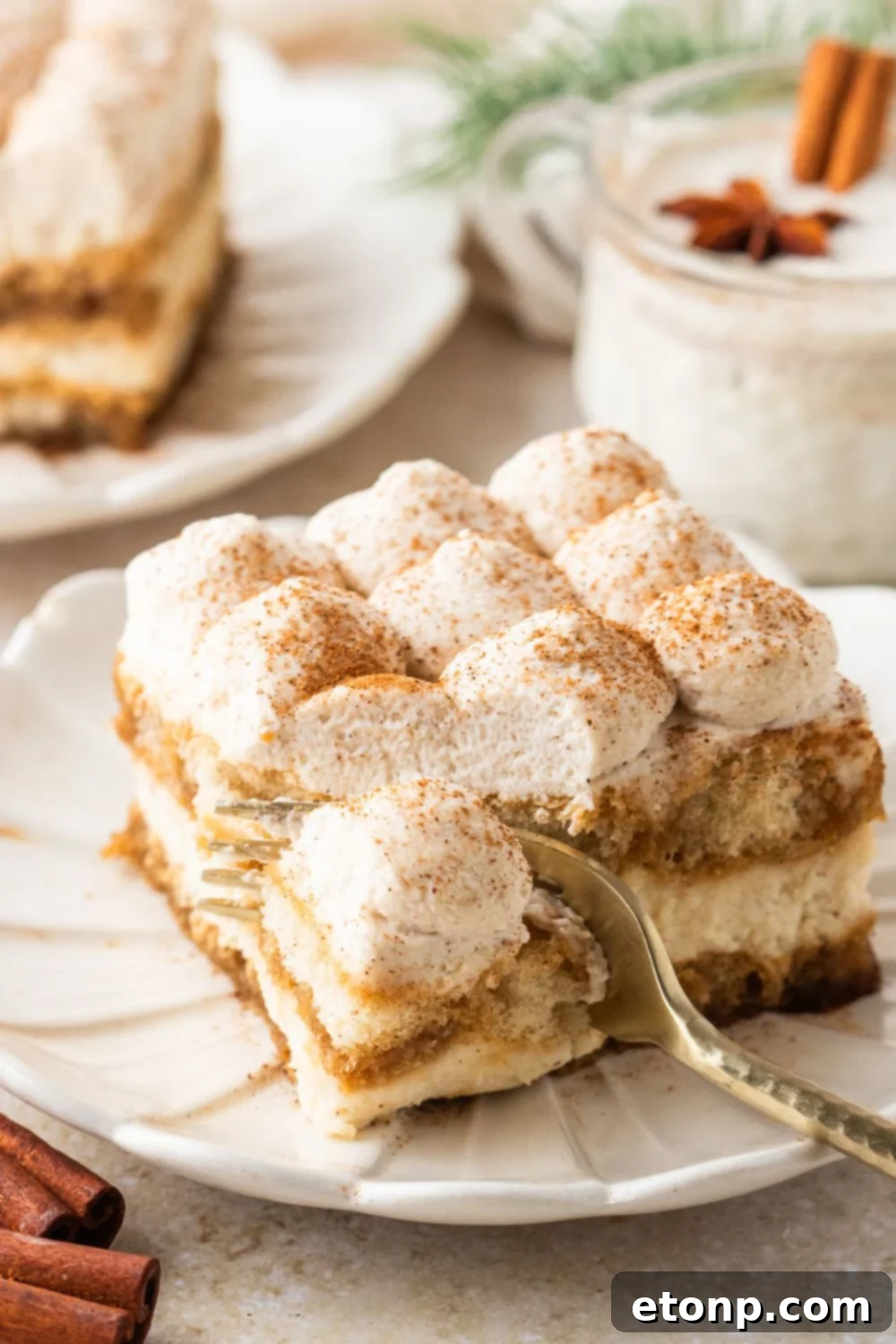 Eggnog Tiramisu: A Festive Holiday Treat 28 Fork cutting into a slice of Eggnog Tiramisu on a white plate on table