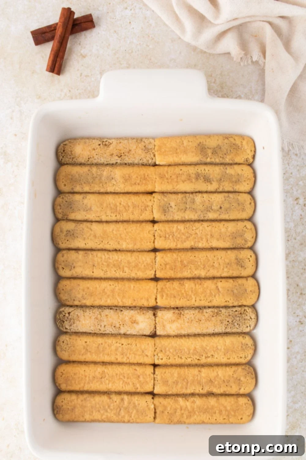 Eggnog Tiramisu: A Festive Holiday Treat 10 A single layer of dipped ladyfinger cookies in a white casserole pan