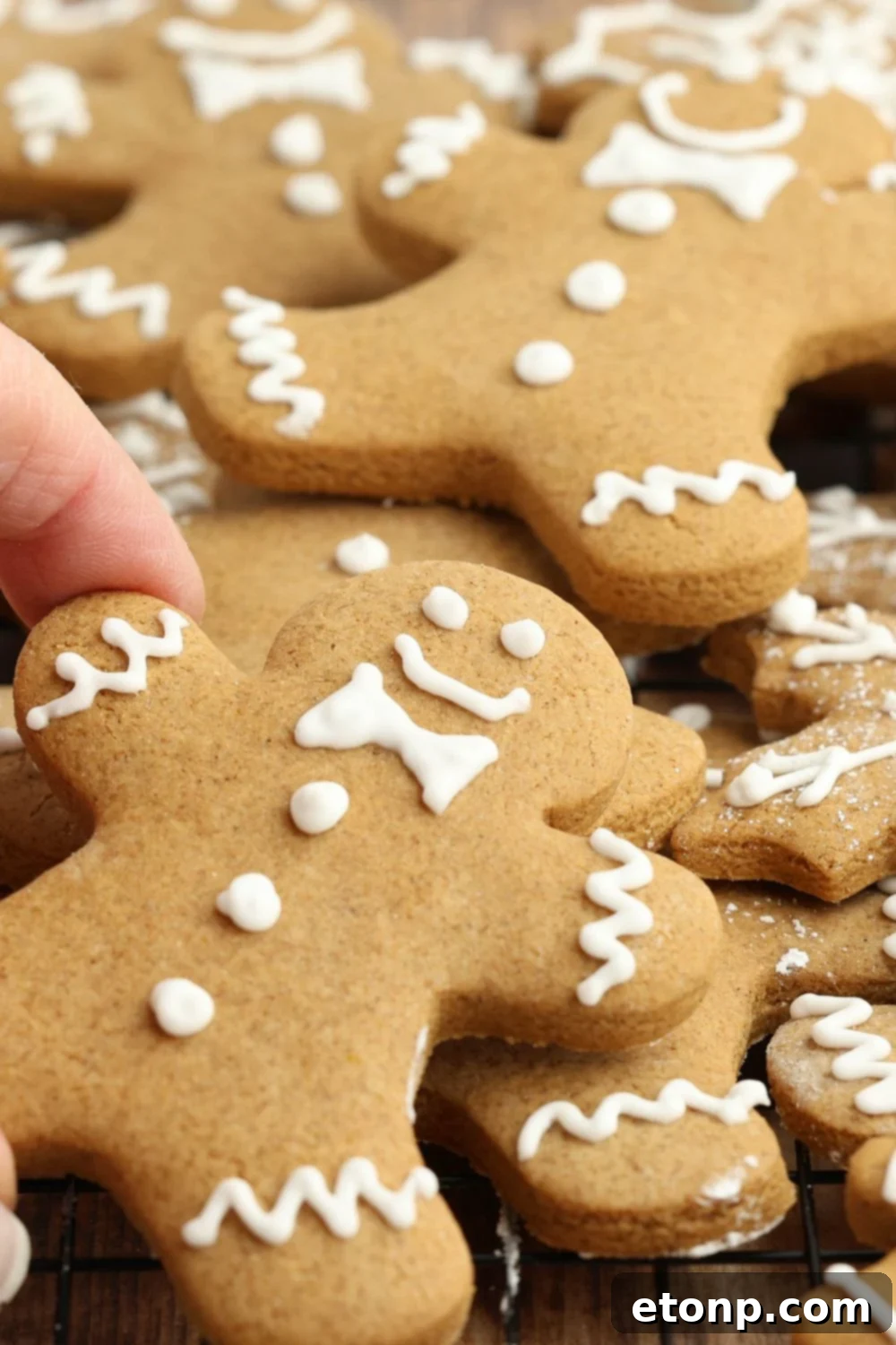 Hand grabbing a gingerbread cookie from a table full of cookies.