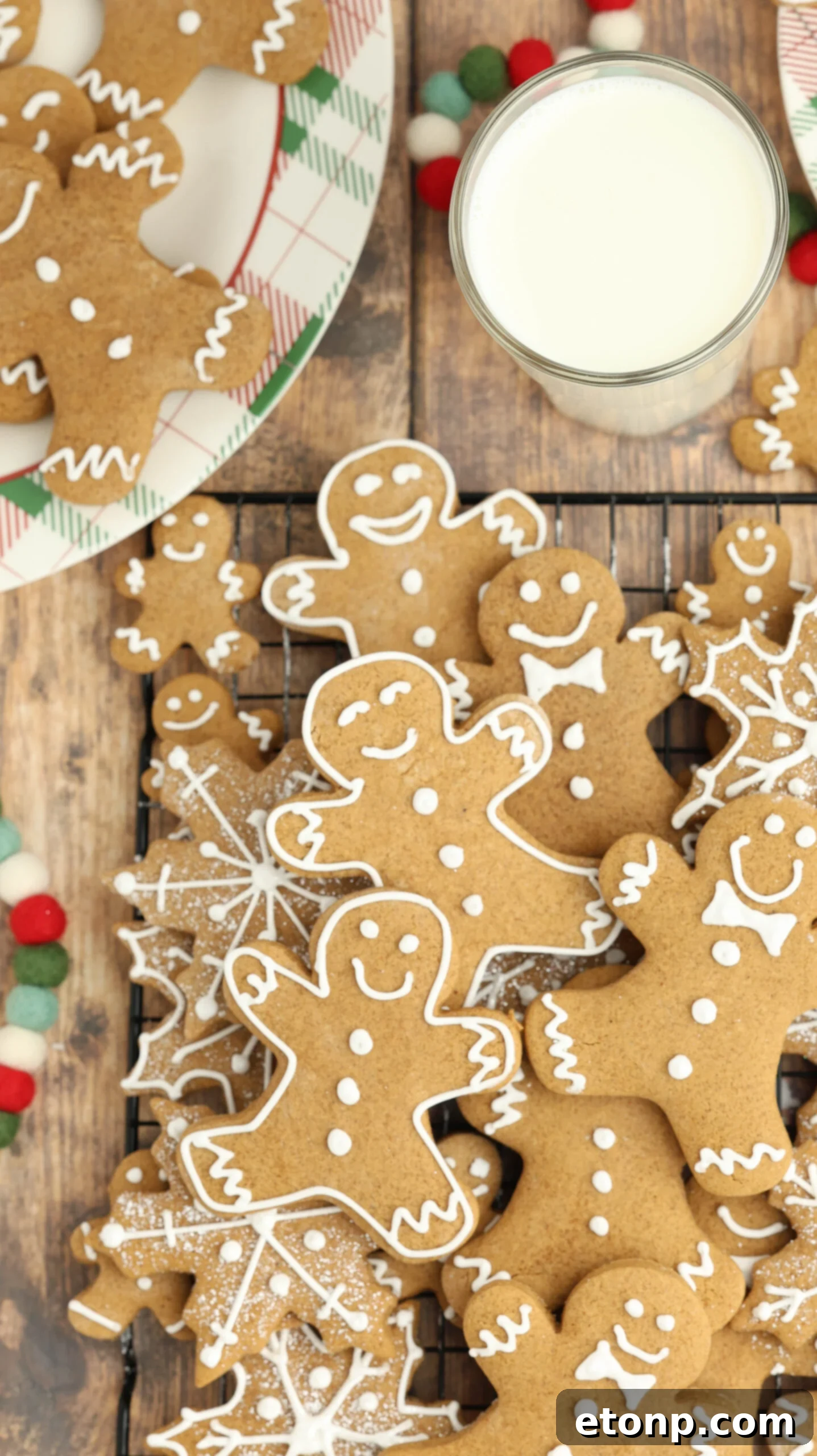 Overhead shot of a cooling rack with Christmas gingerbread cookies and a cup of milk.