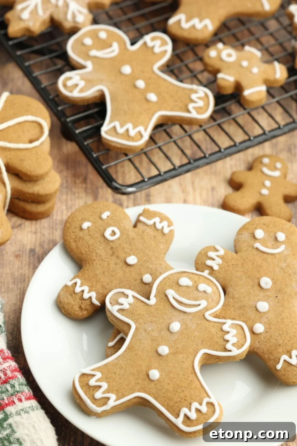 Christmas gingerbread cookies spread around a table, with a cooling rack full of more cookies.