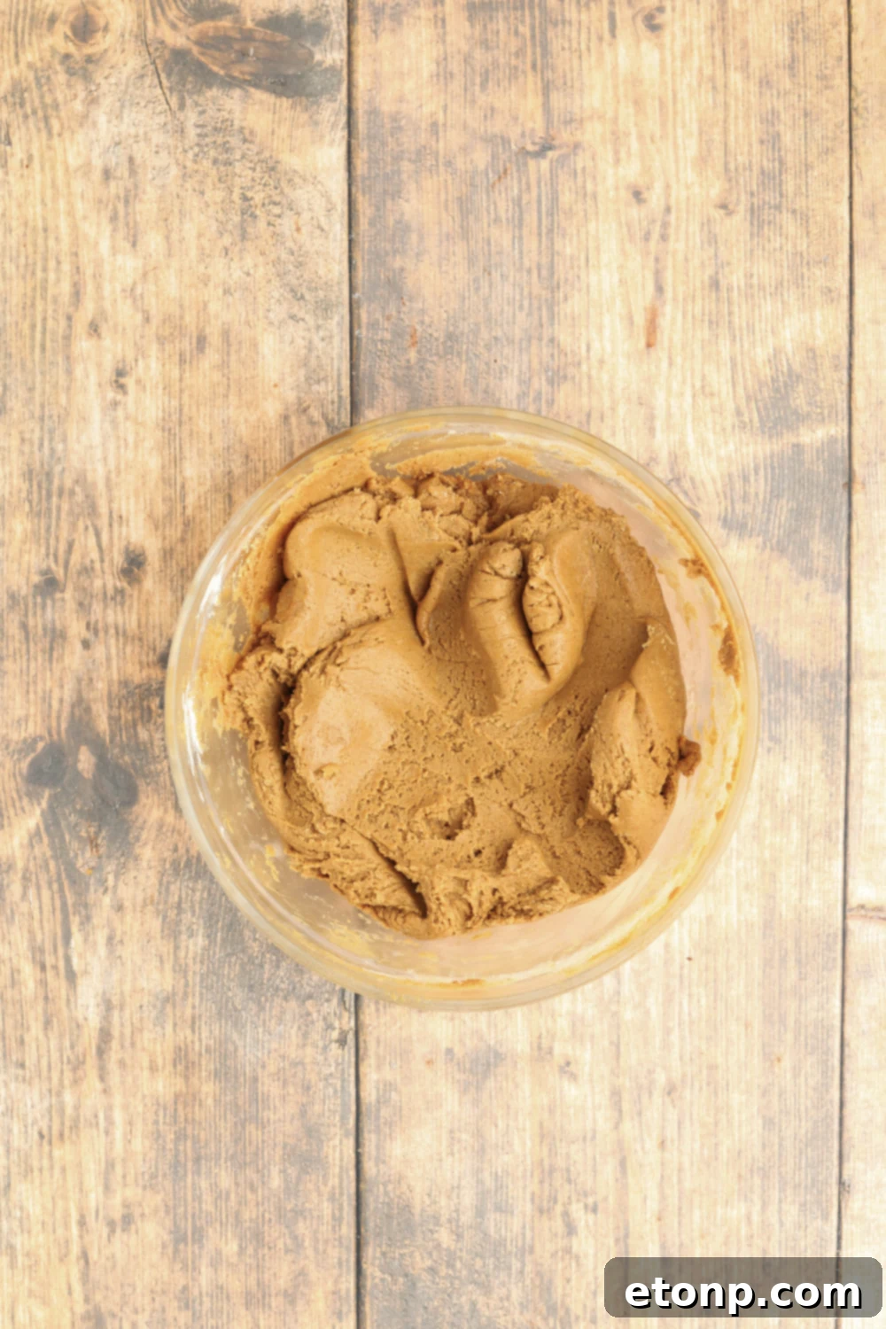 Glass bowl of Christmas gingerbread cookie batter on a wooden table.