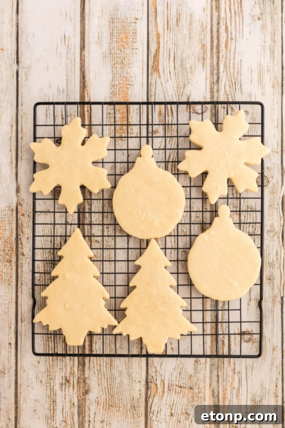 Adorned Sugar Cookies: Soft, Shapely, and Icing-Ready 13 Baked sugar cookies on a cooling rack shaped like Christmas decorations.