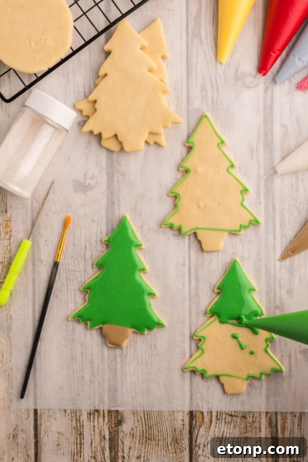 Adorned Sugar Cookies: Soft, Shapely, and Icing-Ready 17 Christmas tree-shaped cookies being piped with royal icing.