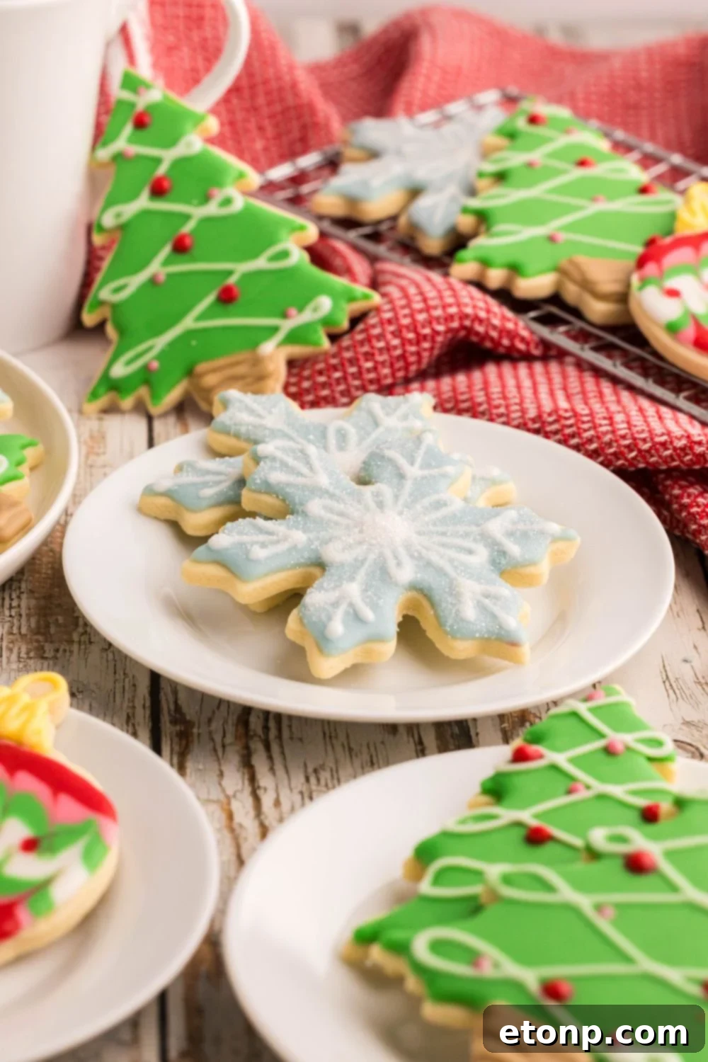 Adorned Sugar Cookies: Soft, Shapely, and Icing-Ready 29 Christmas Decorated Sugar Cookies on small plates with a tray of cookies to the side.