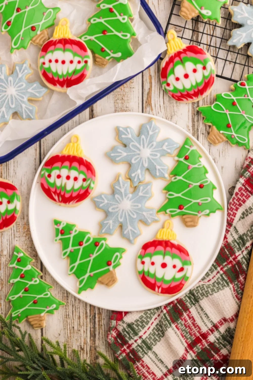 Adorned Sugar Cookies: Soft, Shapely, and Icing-Ready 6 A plate of Christmas Decorated Sugar Cookies with a tray of cookies next to it.