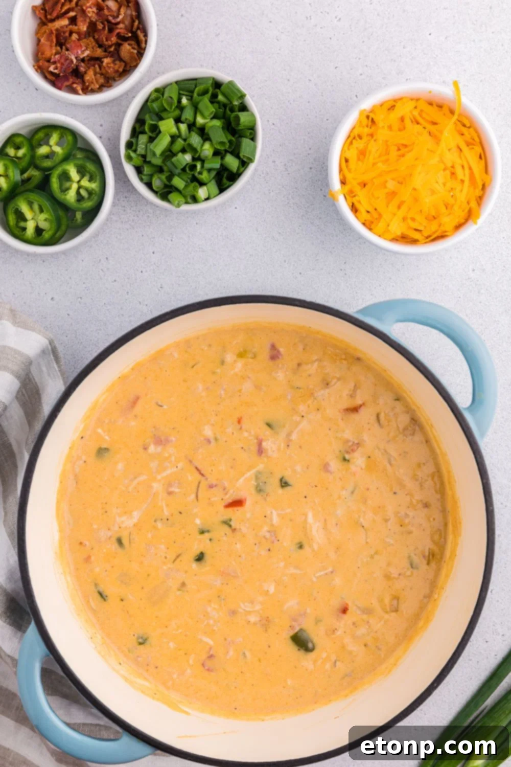 Jalapeño popper crack chicken soup on table with peppers and jalapeños to side in small bowls