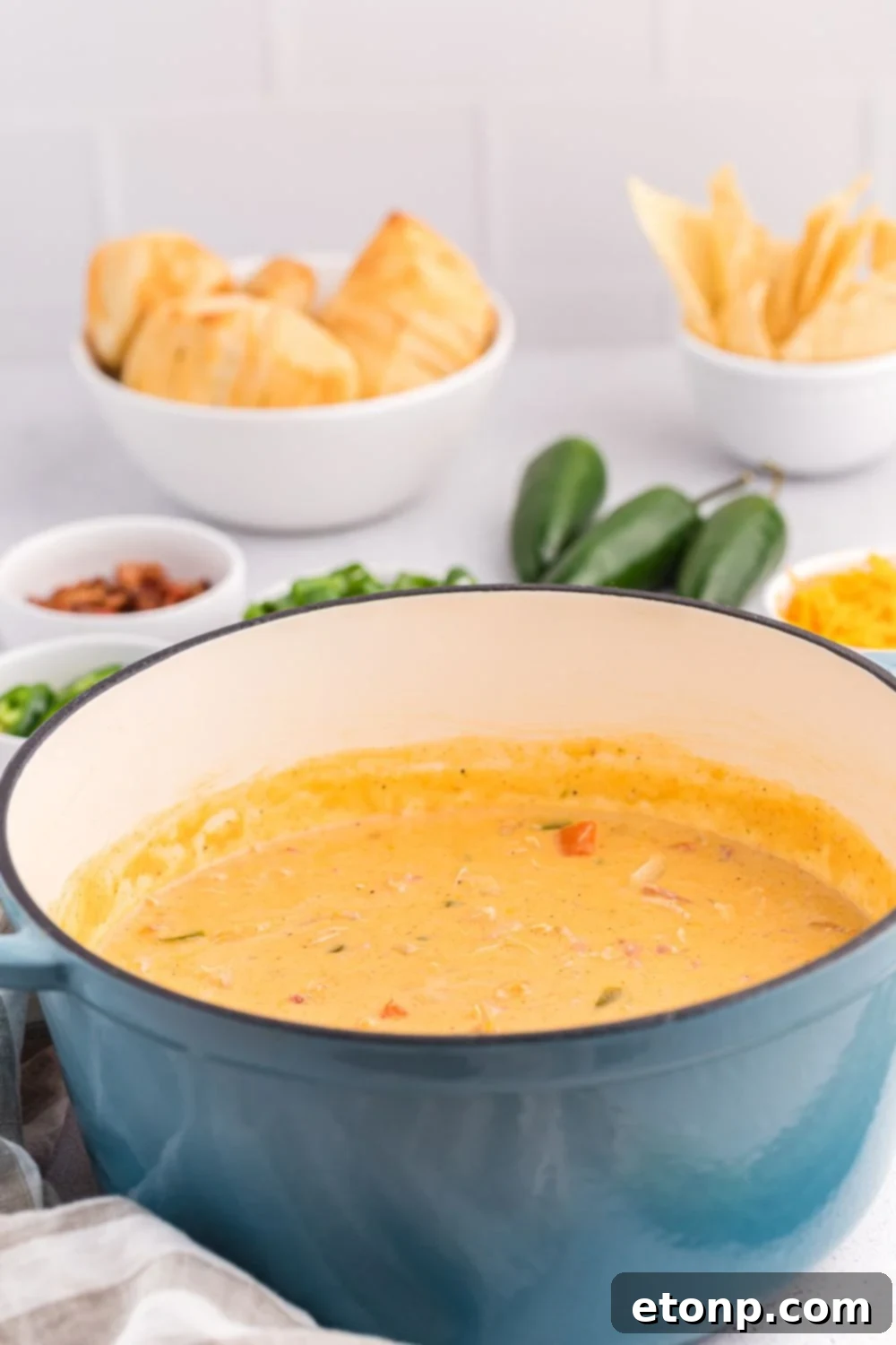 Side view of a pot full of jalapeño popper crack chicken soup with chips behind it on the table