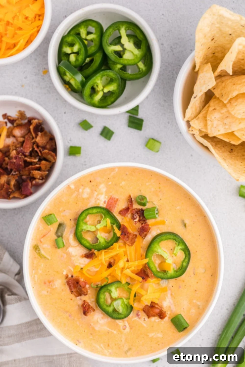 Jalapeño popper crack chicken soup in a bowl with small bowls of back, jalapeños, and chips and cheese
