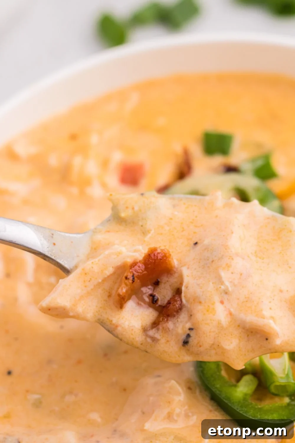 Jalapeño popper crack chicken soup in a bowl with a spoon scooping up some of the soup